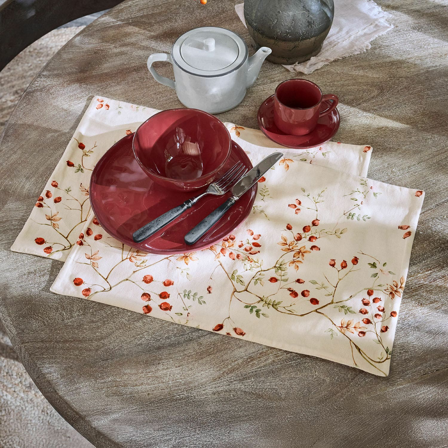 Set de 2 manteles individuales Mauriac Vajilla cerámica roja sobre mantel de lino con diseño de frutos en mesa de madera