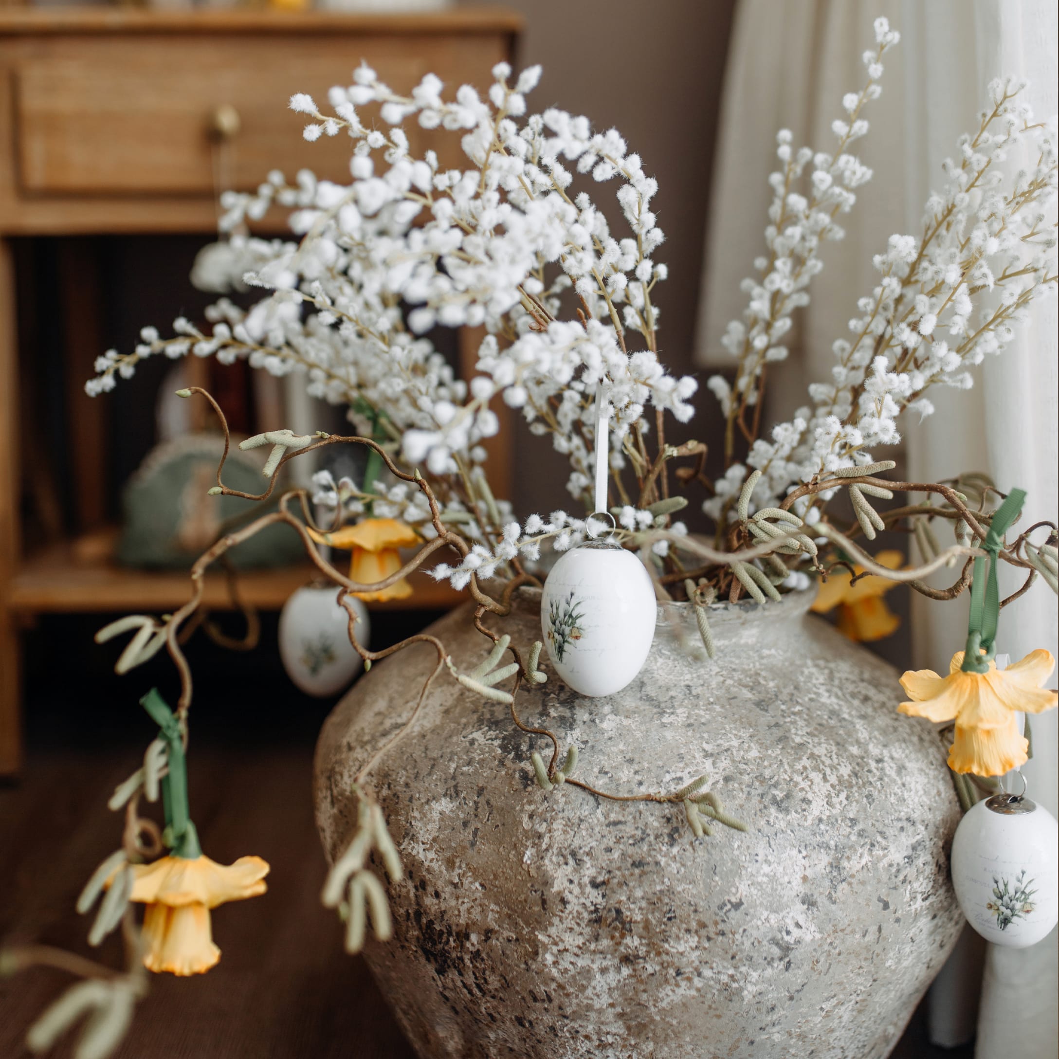 Jarrón de cerámica gris con ramas blancas y flores amarillas para decoración primaveral interior