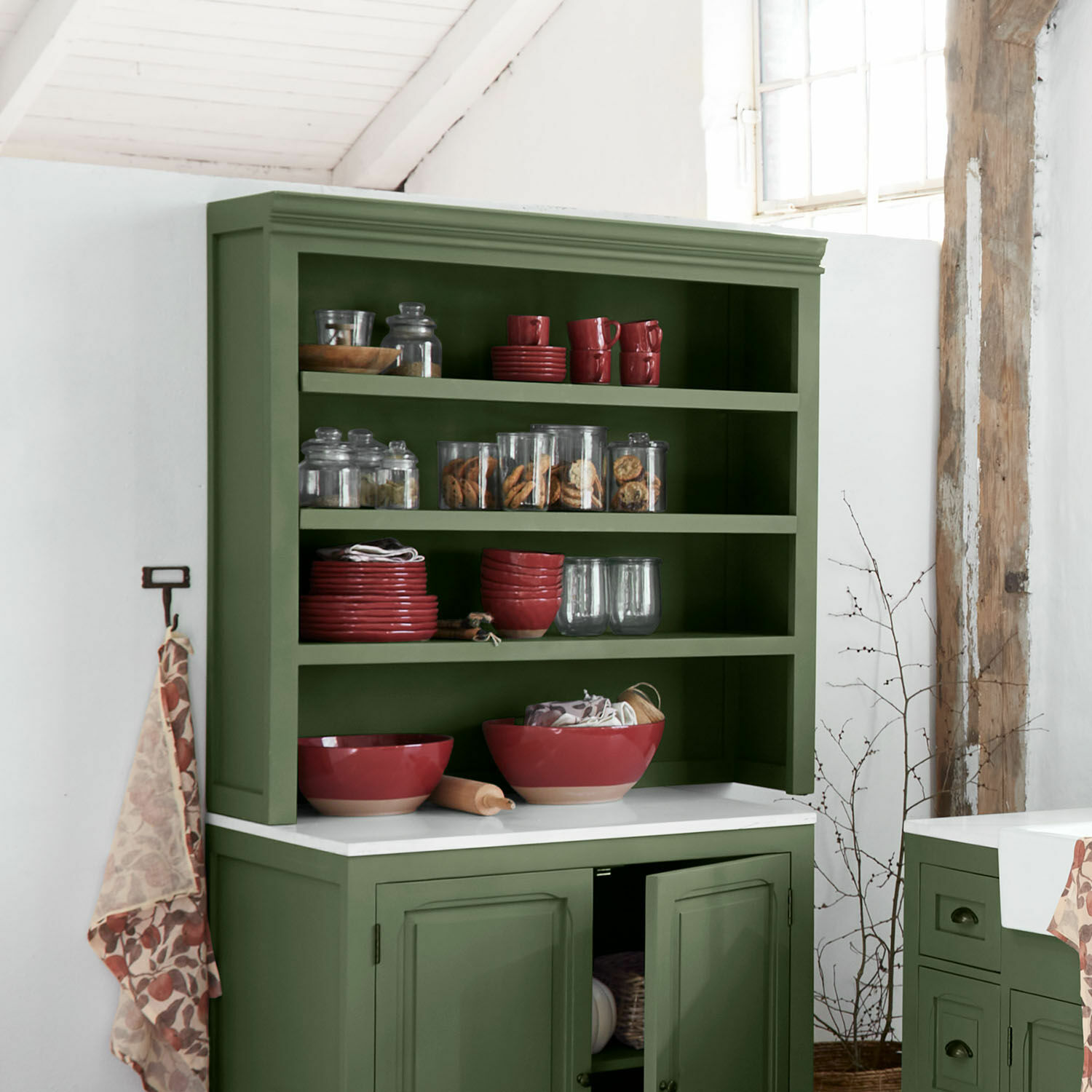 Estante superior de cocina Lansbury Aparador verde de madera con cuencos rojos de cerámica y frascos de vidrio con galletas en cocina rústica