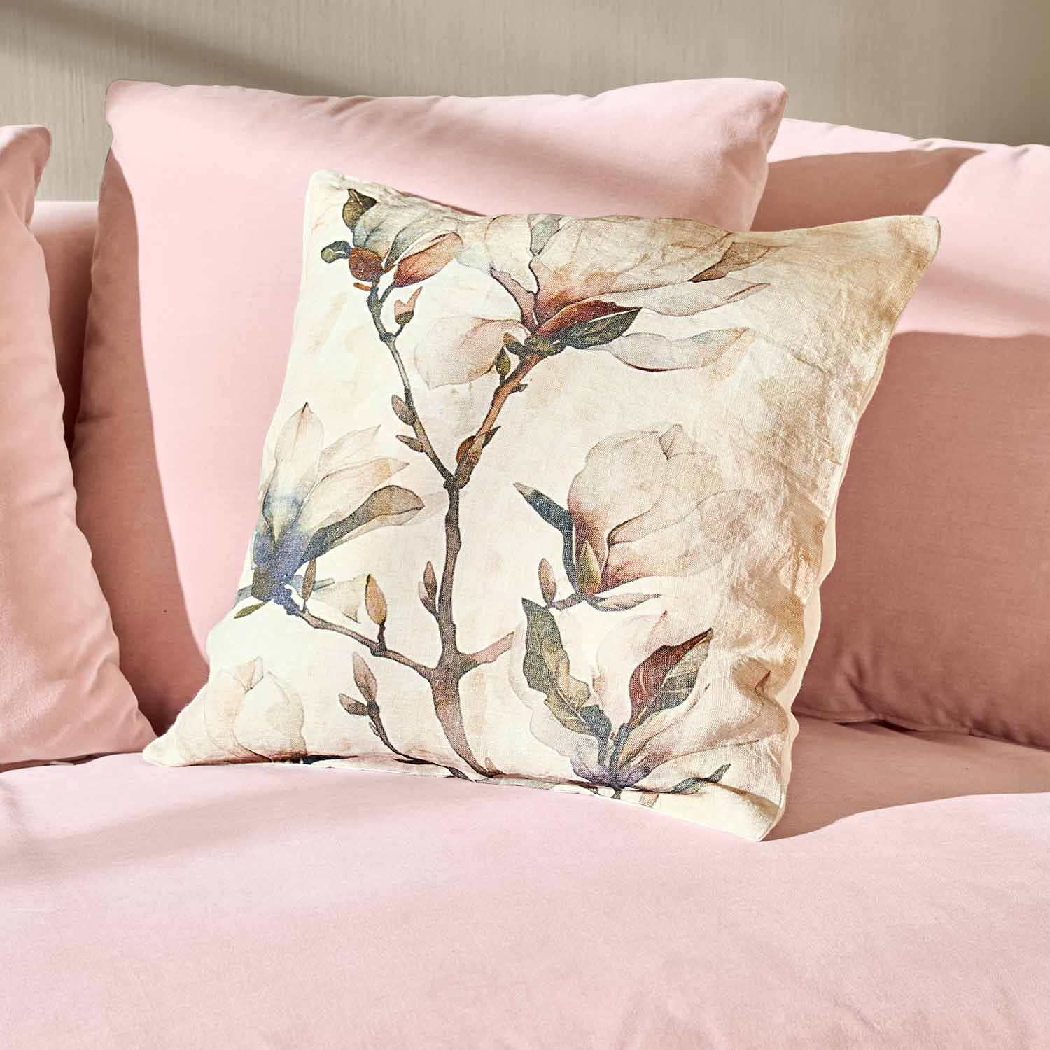 Cojín decorativo de algodón con estampado floral sobre sofá rosa, accesorio elegante para el hogar