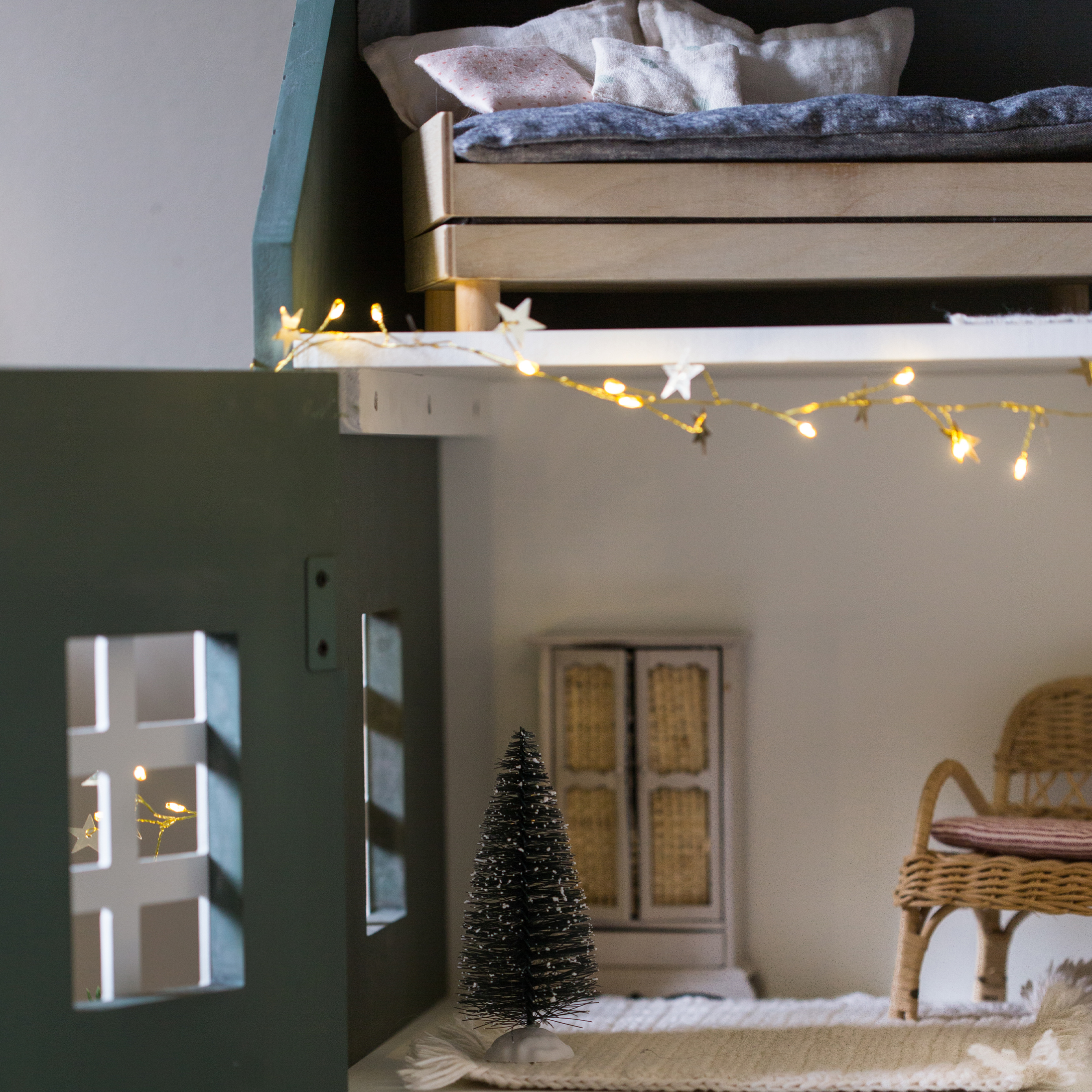 Pequeño árbol decorativo negro de fibra sobre alfombra blanca en habitación infantil acogedora con luces
