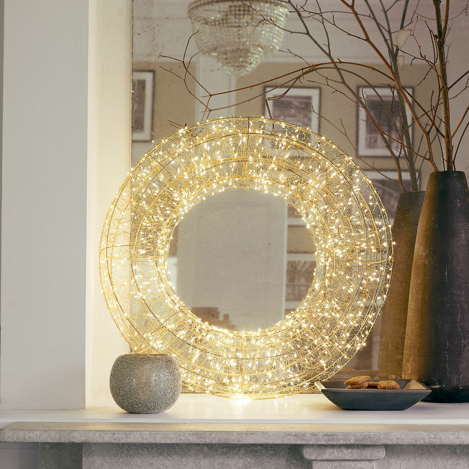 Corona LED Veralisse Decoración redonda de alambre dorado con luces LED cálidas sobre la repisa de la chimenea