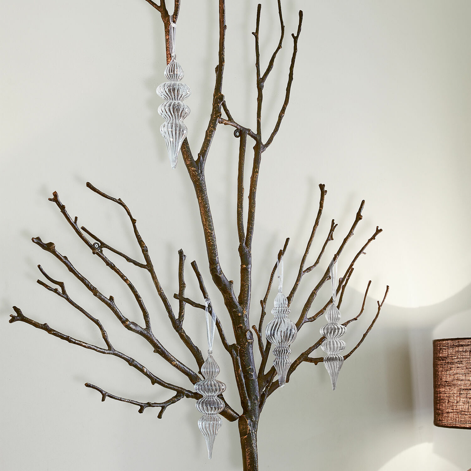 Set de 4 adornos navideños Diorise Adornos transparentes colgados en ramas oscuras sobre fondo claro, decoración de interiores