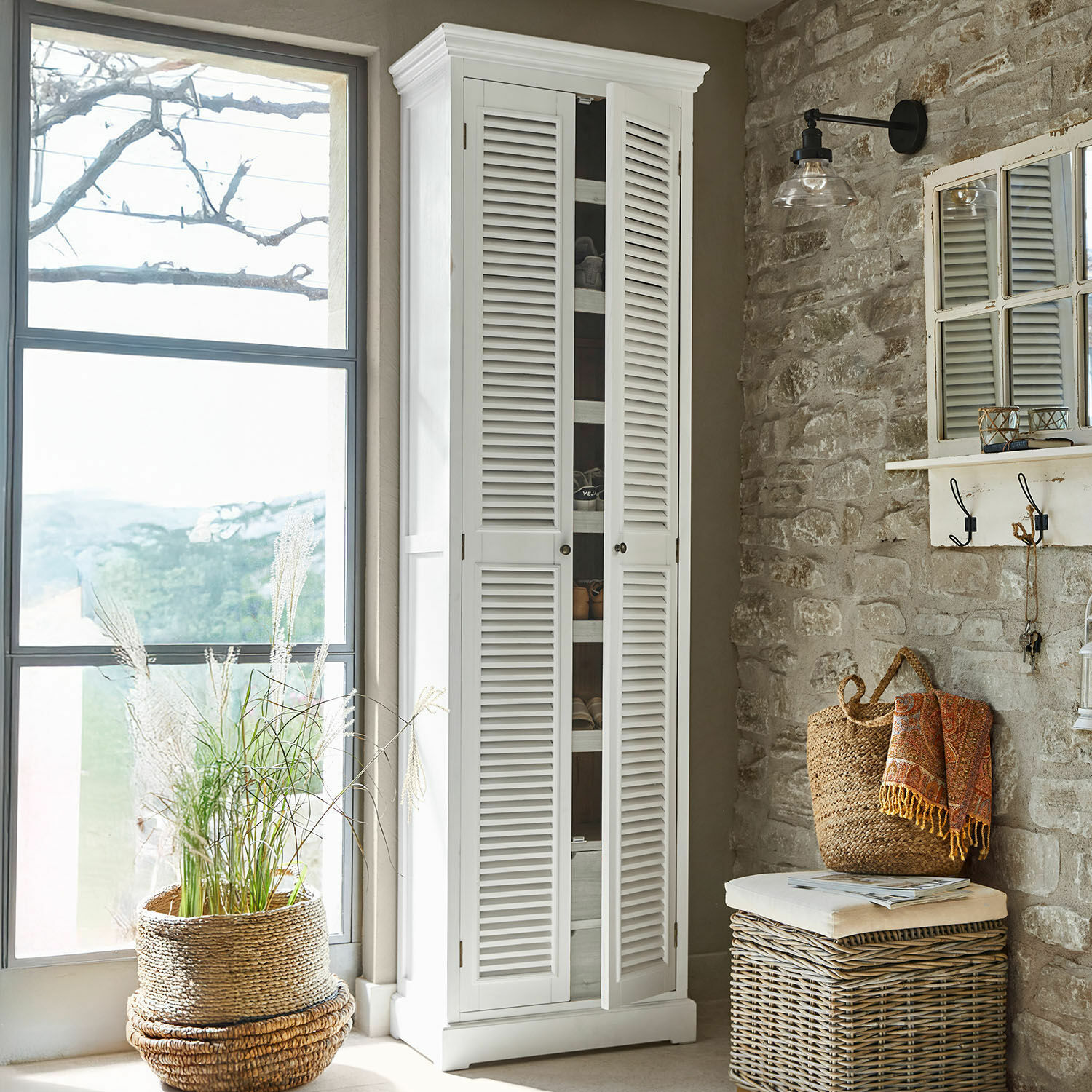 Mueble zapatero Blossomby Armario blanco de madera con puertas de persiana en interior rústico con pared de piedra