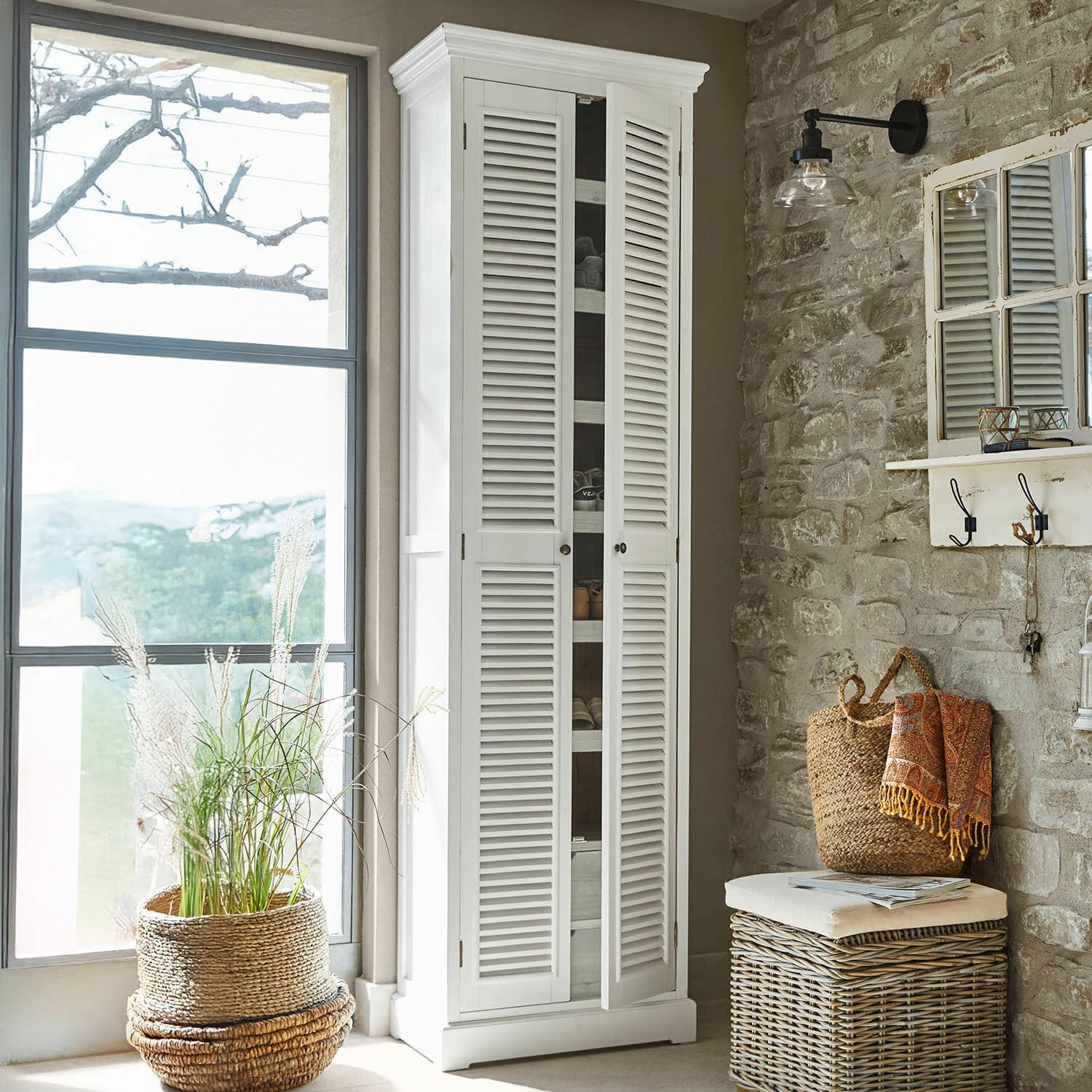 Mueble zapatero Blossomby Armario blanco de madera con puertas de persiana en interior rústico con pared de piedra