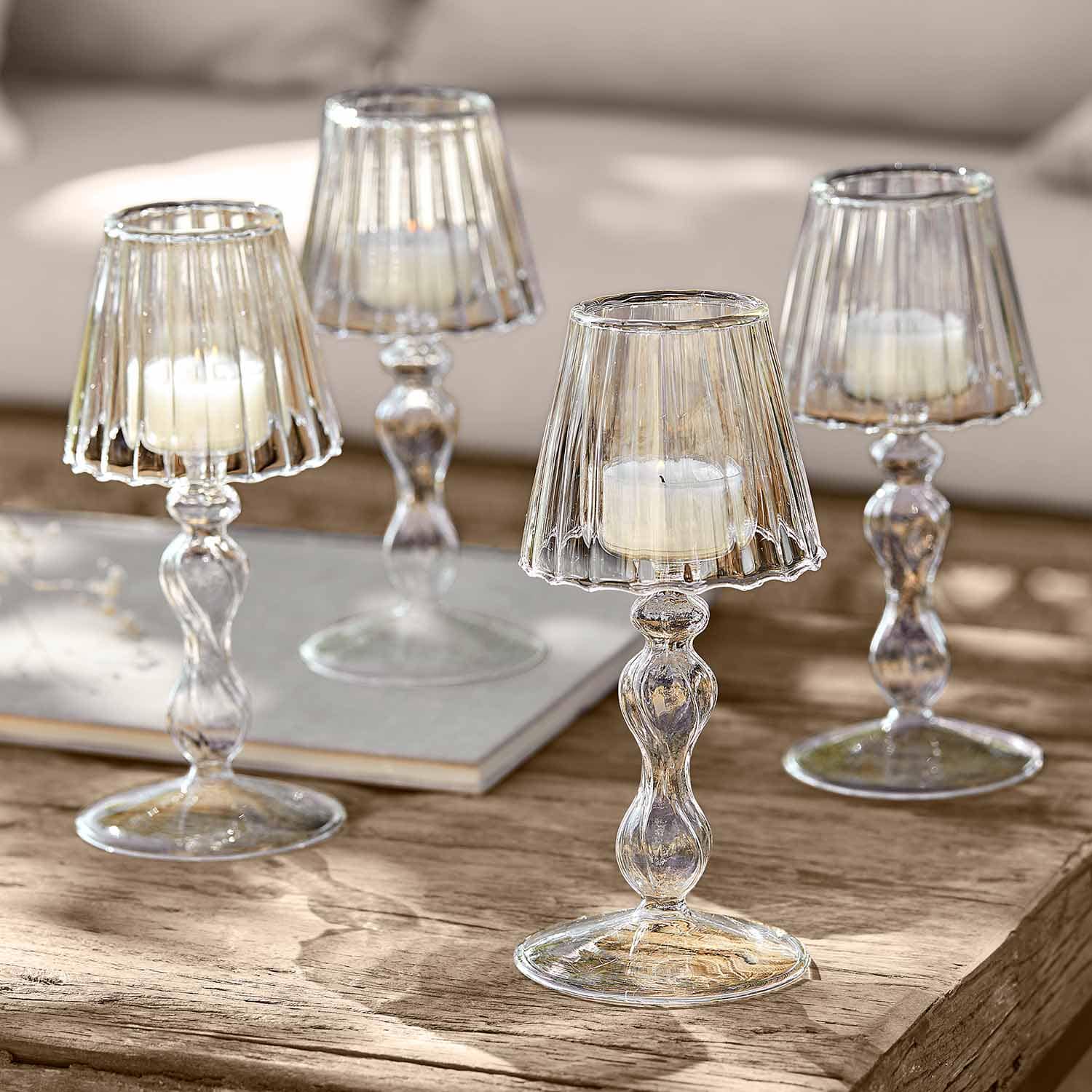 Portavelas de cristal transparente con velas blancas sobre mesa de madera para decoración