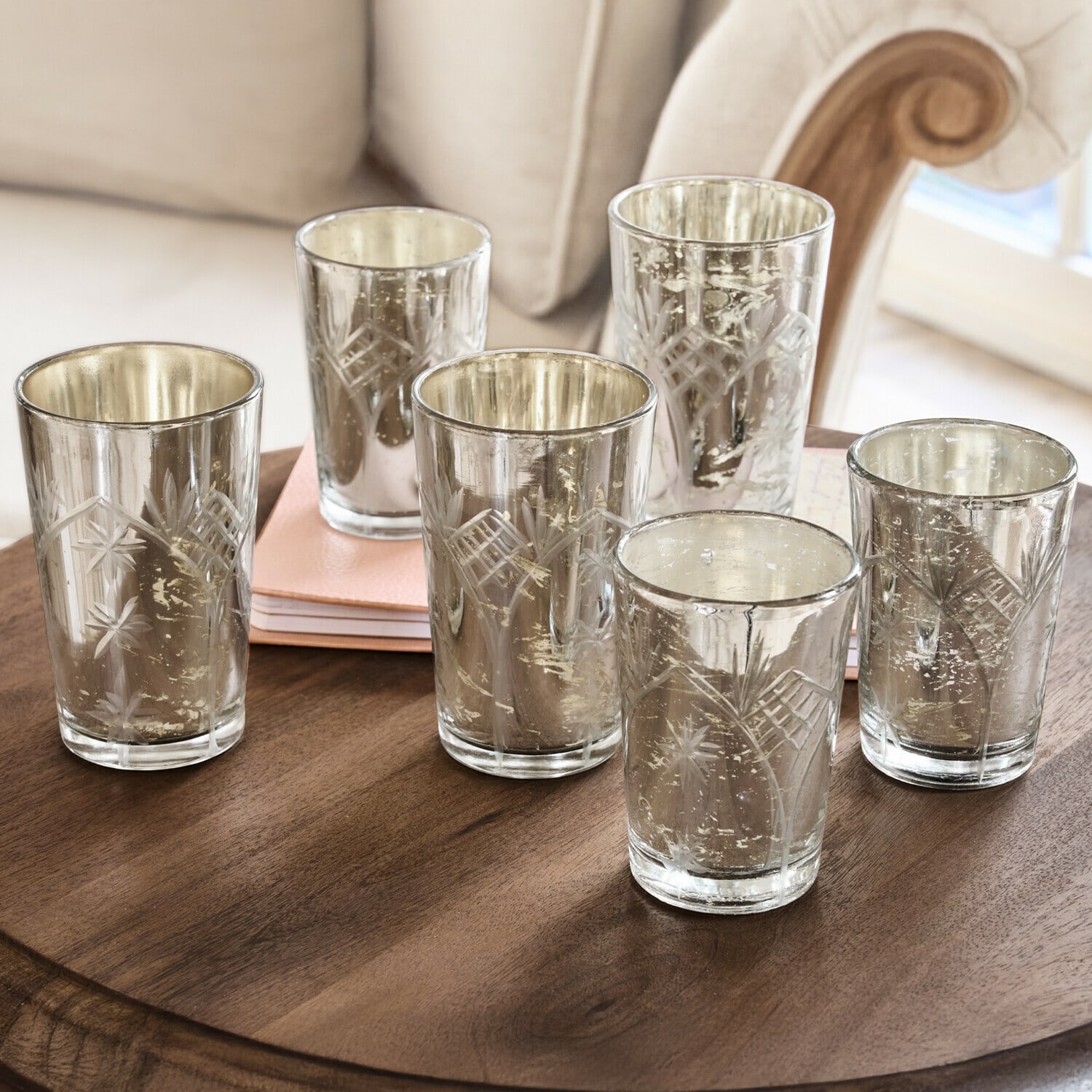 Set de 6 portavelas Latona Conjunto de seis portavelas de vidrio grabado con acabado plateado sobre mesa de madera