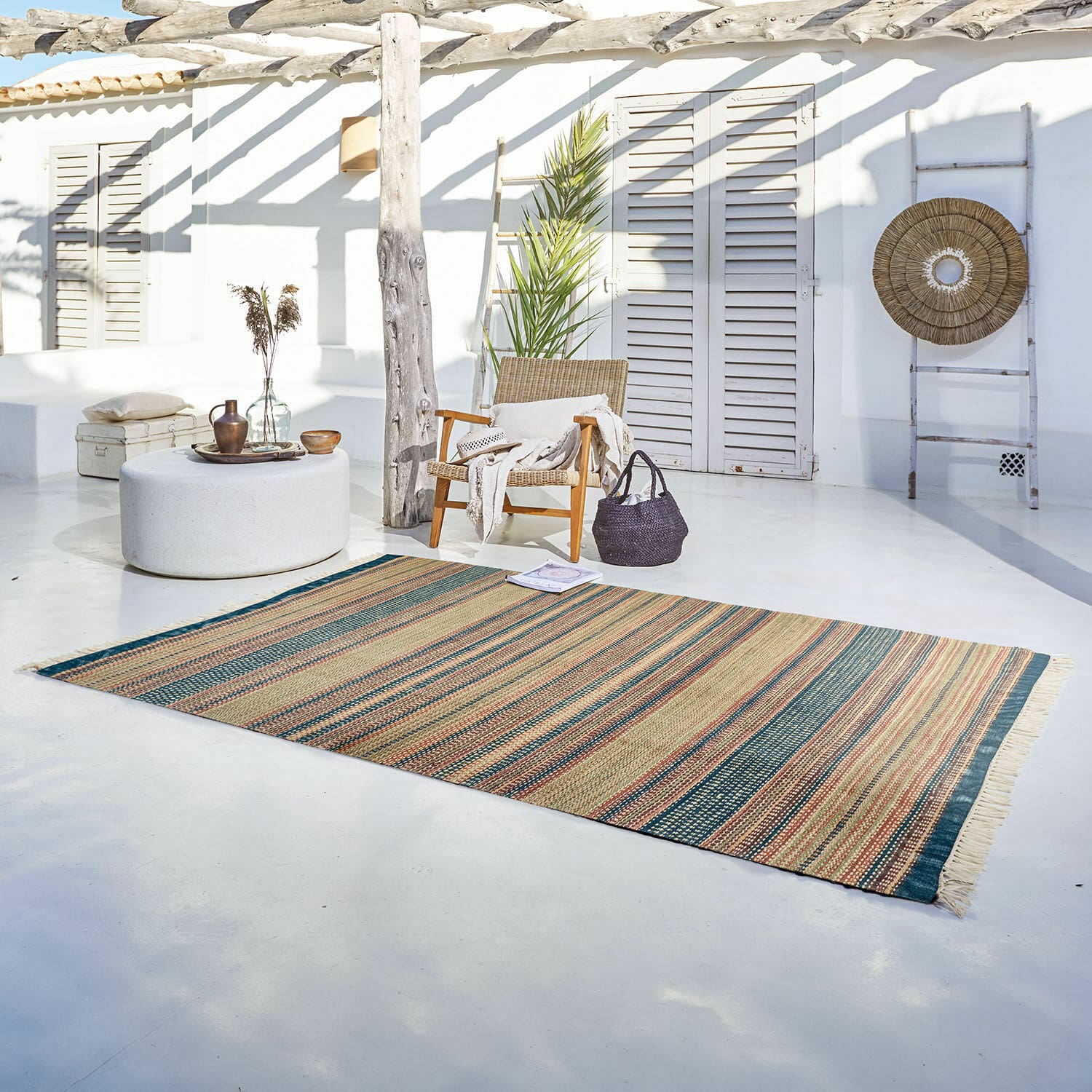Alfombra para interior y exterior Atlanta Alfombra de material natural con rayas en tonos beige y verde sobre terraza luminosa