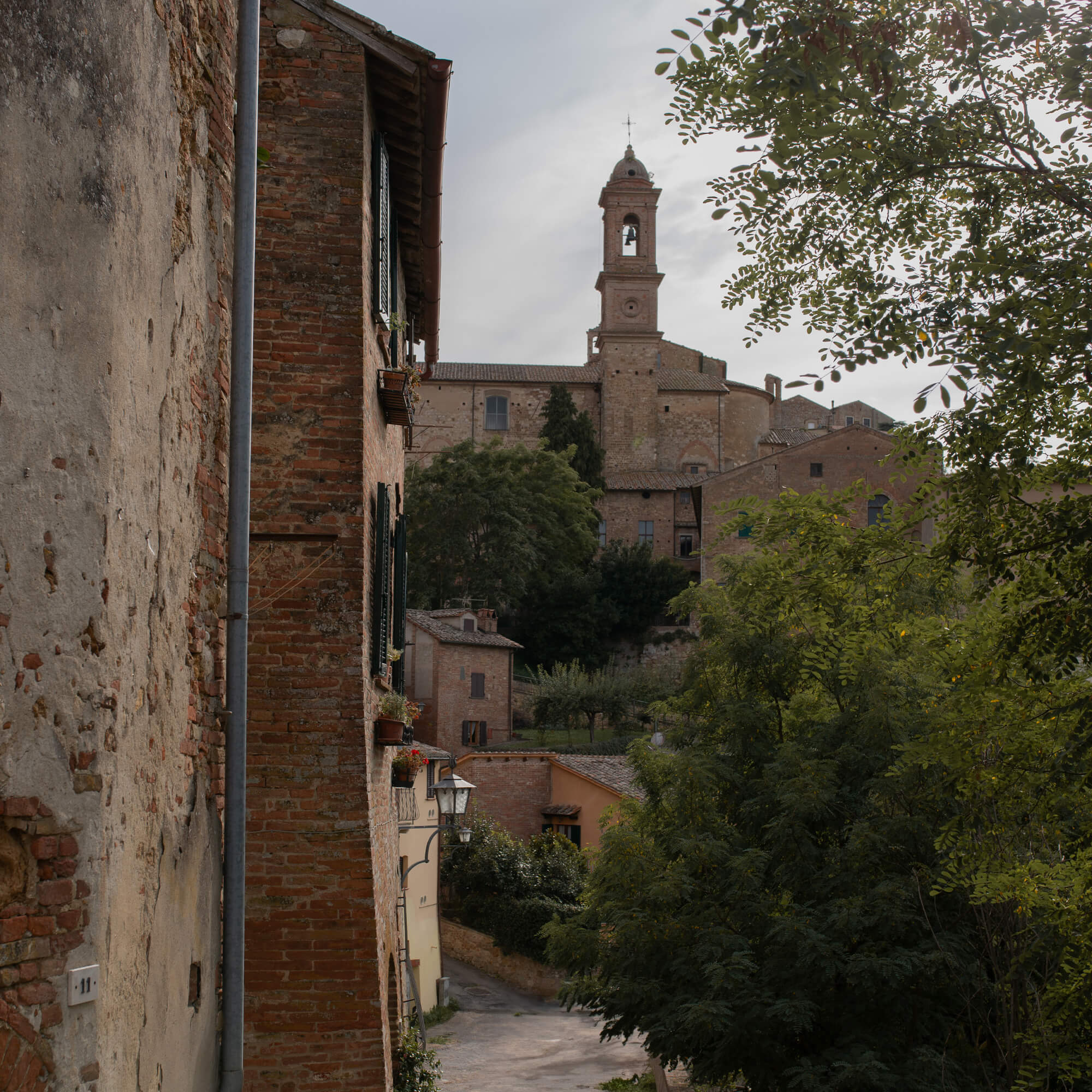 Vista de una calle antigua de piedra con edificios de ladrillo y campanario de iglesia al fondo