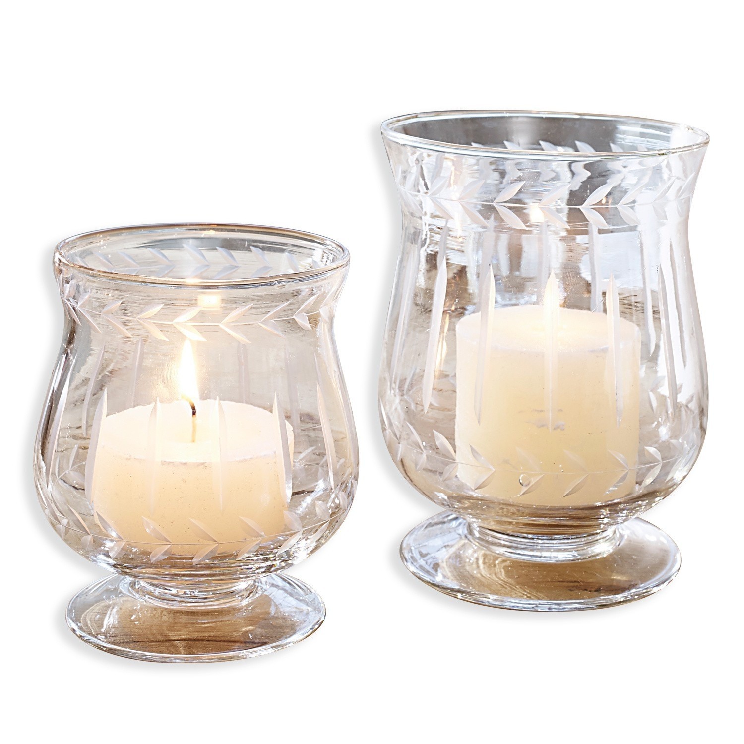 Set de 2 portavelas Moon Dos portavelas de vidrio transparente con diseño grabado de hojas y velas blancas encendidas