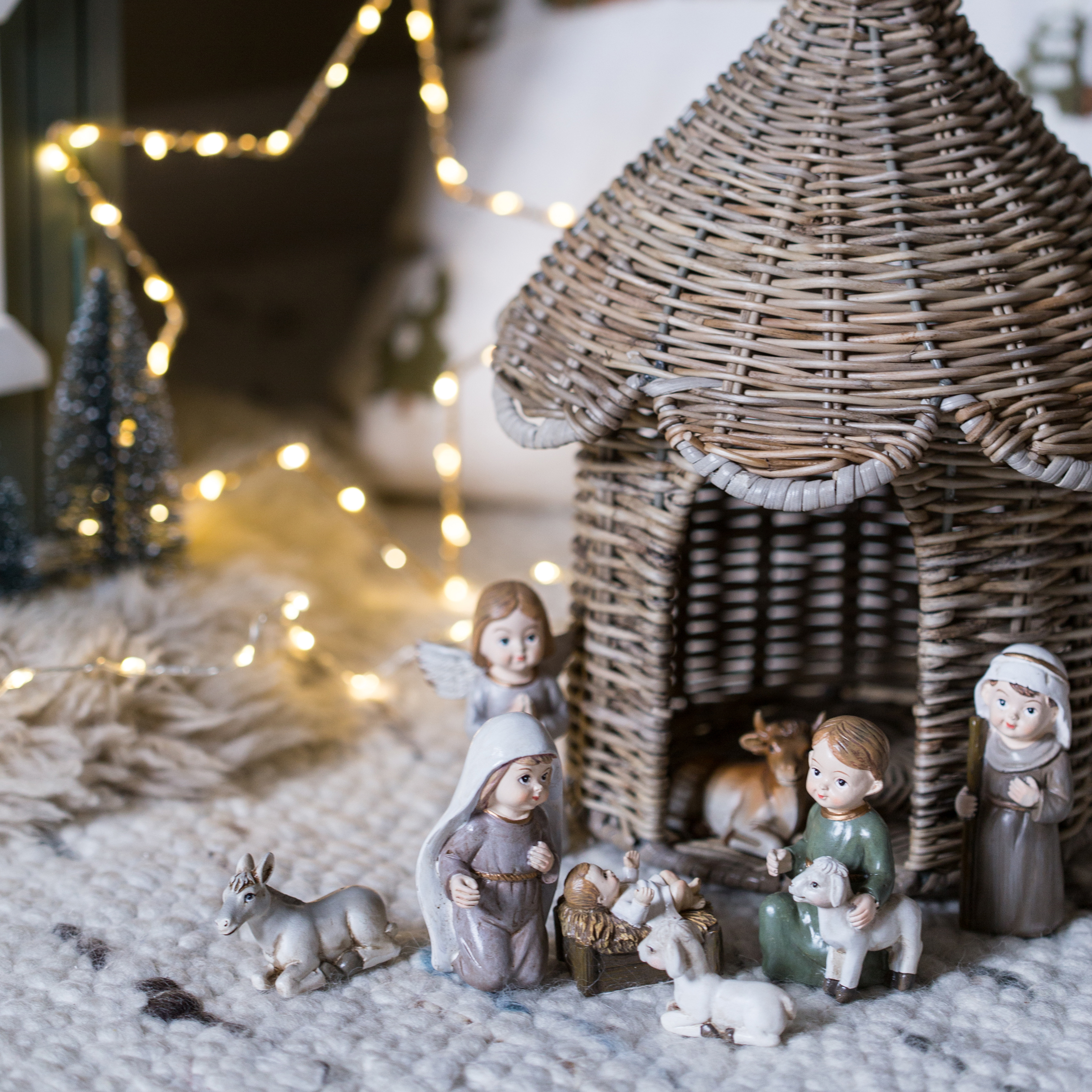 Figuras de belén navideño con casa de mimbre y personajes sobre alfombra suave con luces LED