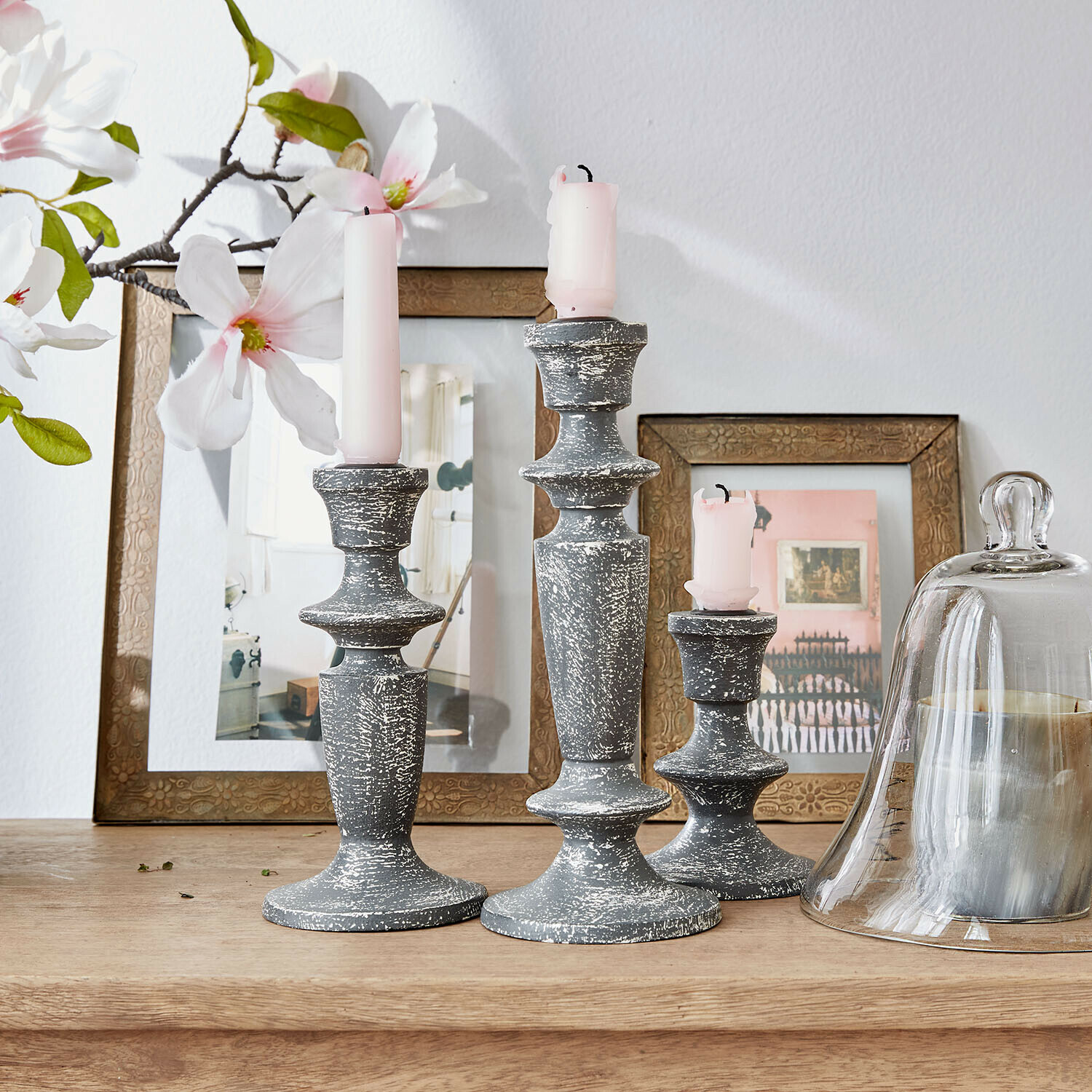 Set de 3 candeleros Ténébrelle Conjunto de tres candelabros de madera gris envejecida con velas rosas sobre mesa de madera