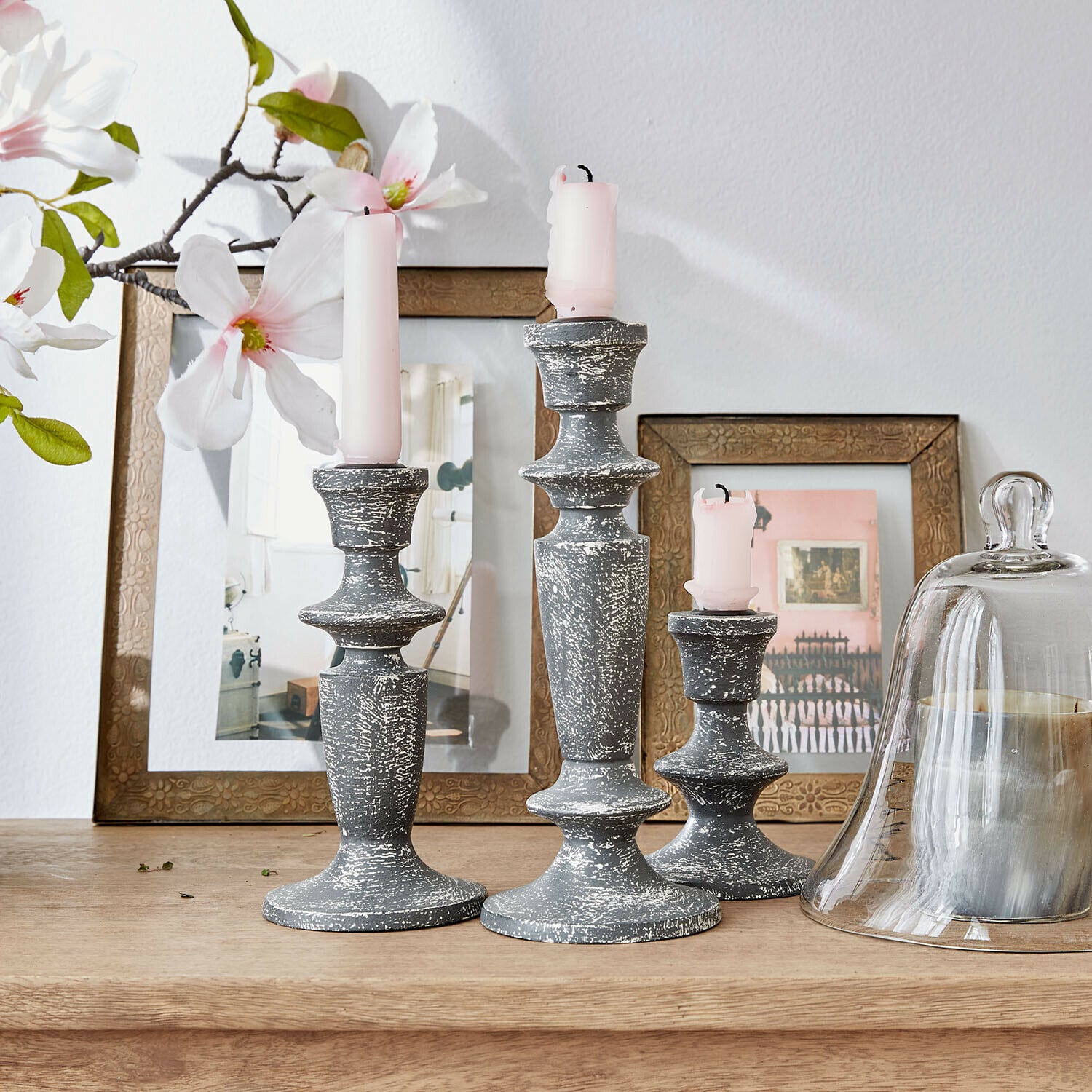 Set de 3 candeleros Ténébrelle Conjunto de tres candelabros de madera gris envejecida con velas rosas sobre mesa de madera