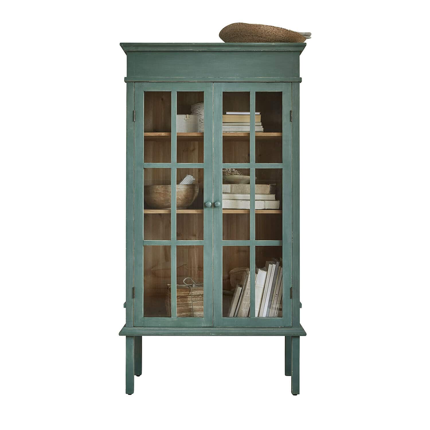 Vitrina Faymere Vitrina de madera verde con puertas de cristal y estantes con libros y objetos decorativos
