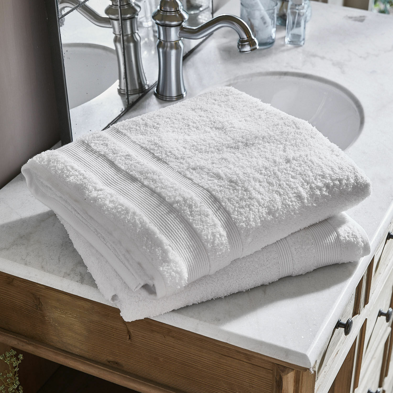 Set de 2 toallas de baño Bourogne Toallas blancas de algodón dobladas sobre lavabo de mármol con mueble de madera en baño