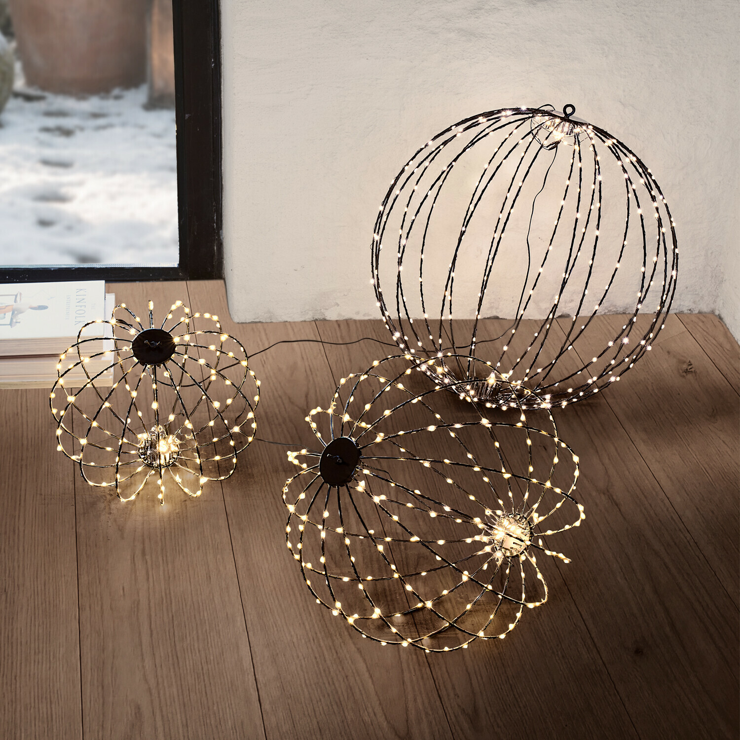 Set de 3 esferas LED Brilliante Dos esferas decorativas con luces LED blancas cálidas en el suelo de una sala de estar moderna