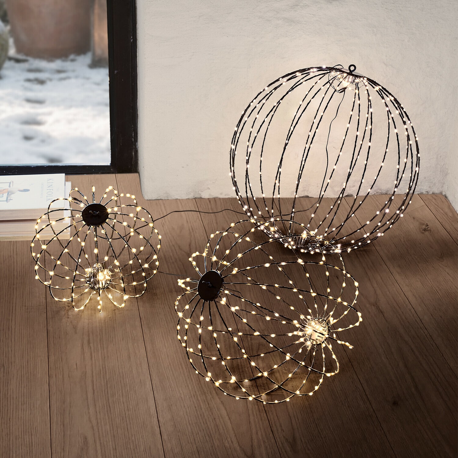 Set de 3 esferas LED Brilliante Dos esferas decorativas con luces LED blancas cálidas en el suelo de una sala de estar moderna