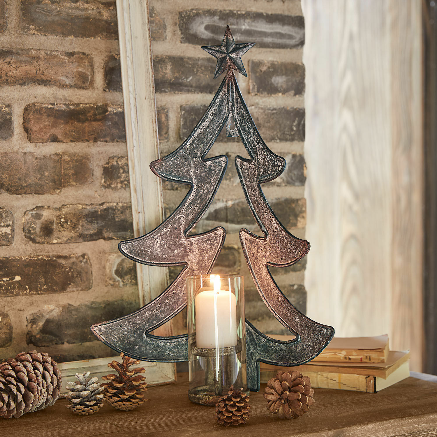 Portavelas de pared Jolise Decoración de árbol de Navidad de metal con estrella y vela en portavelas de vidrio sobre mesa de madera con piñas