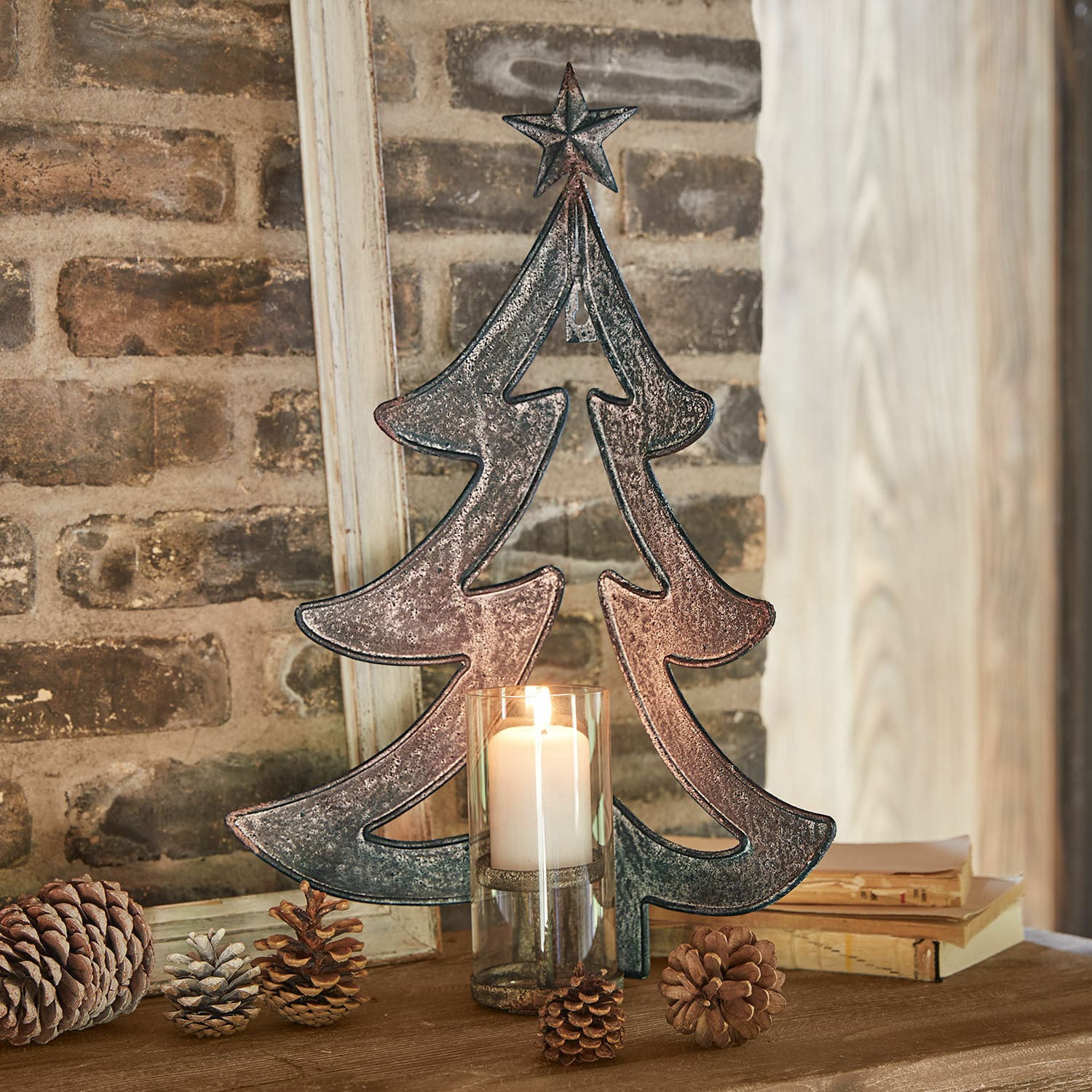 Portavelas de pared Jolise Decoración de árbol de Navidad de metal con estrella y vela en portavelas de vidrio sobre mesa de madera con piñas