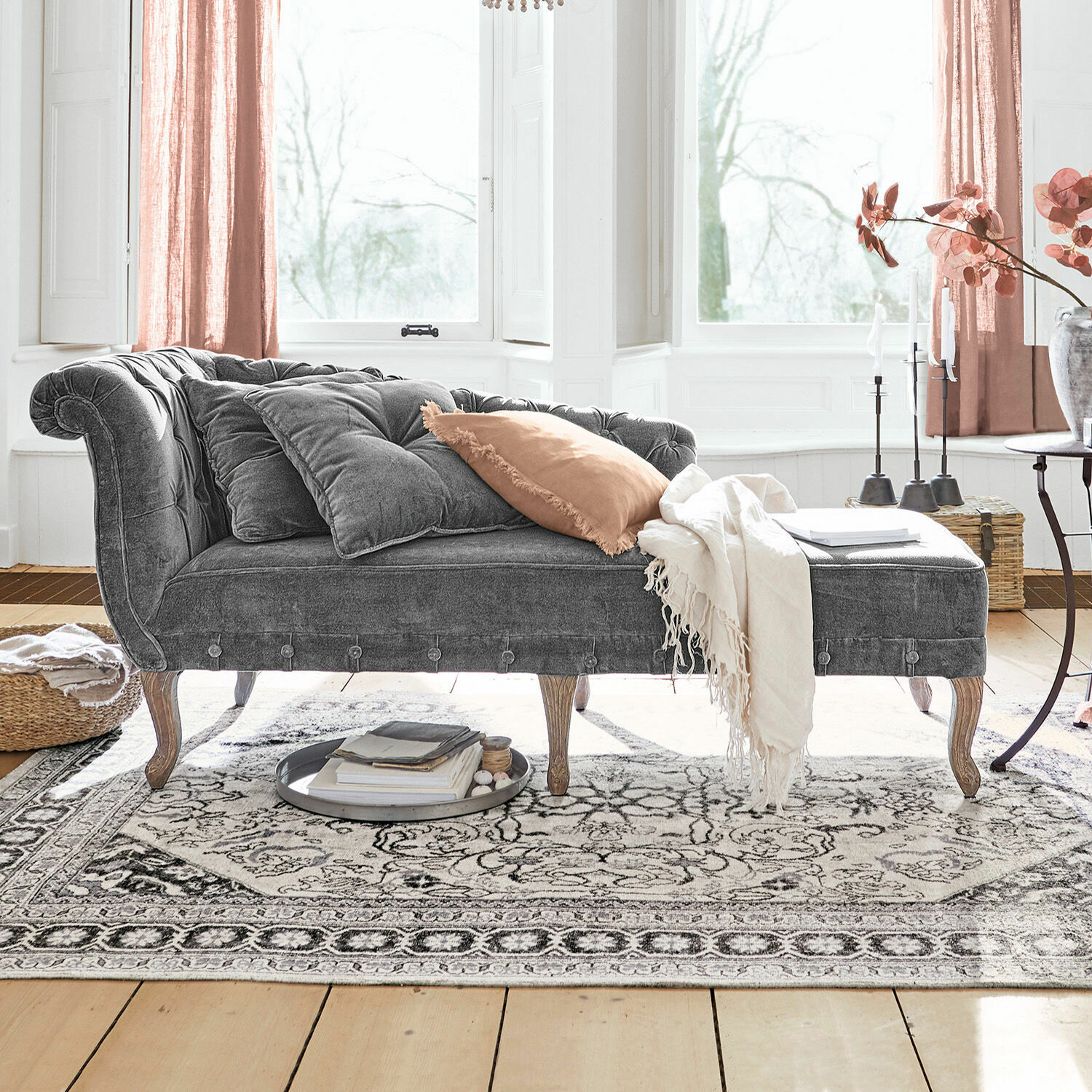 Chaise longue Viviani Chaise longue de terciopelo gris con patas de madera y cojines claros en sala luminosa