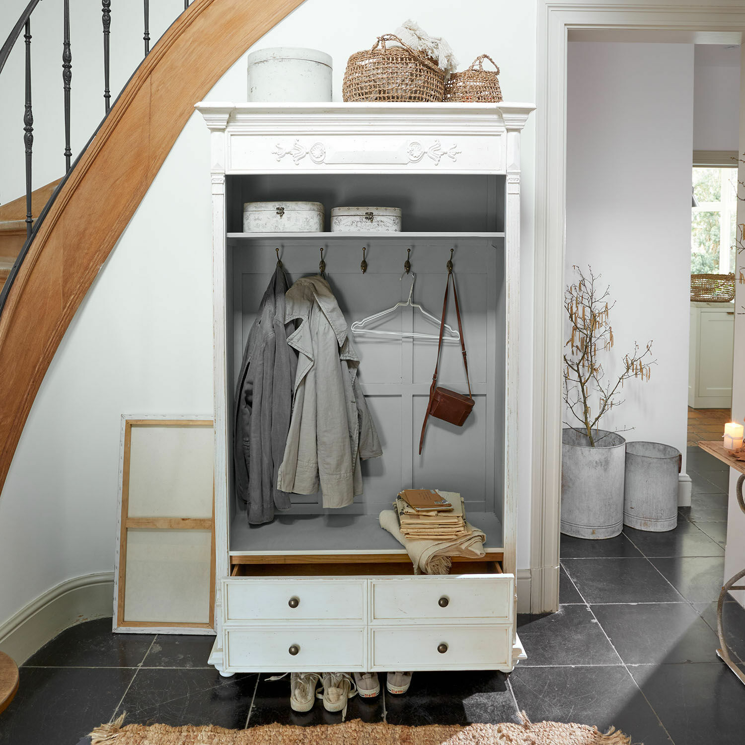 Mueble recibidor Étourville Armario blanco de madera con ganchos, cajones y cestas decorativas en un recibidor luminoso