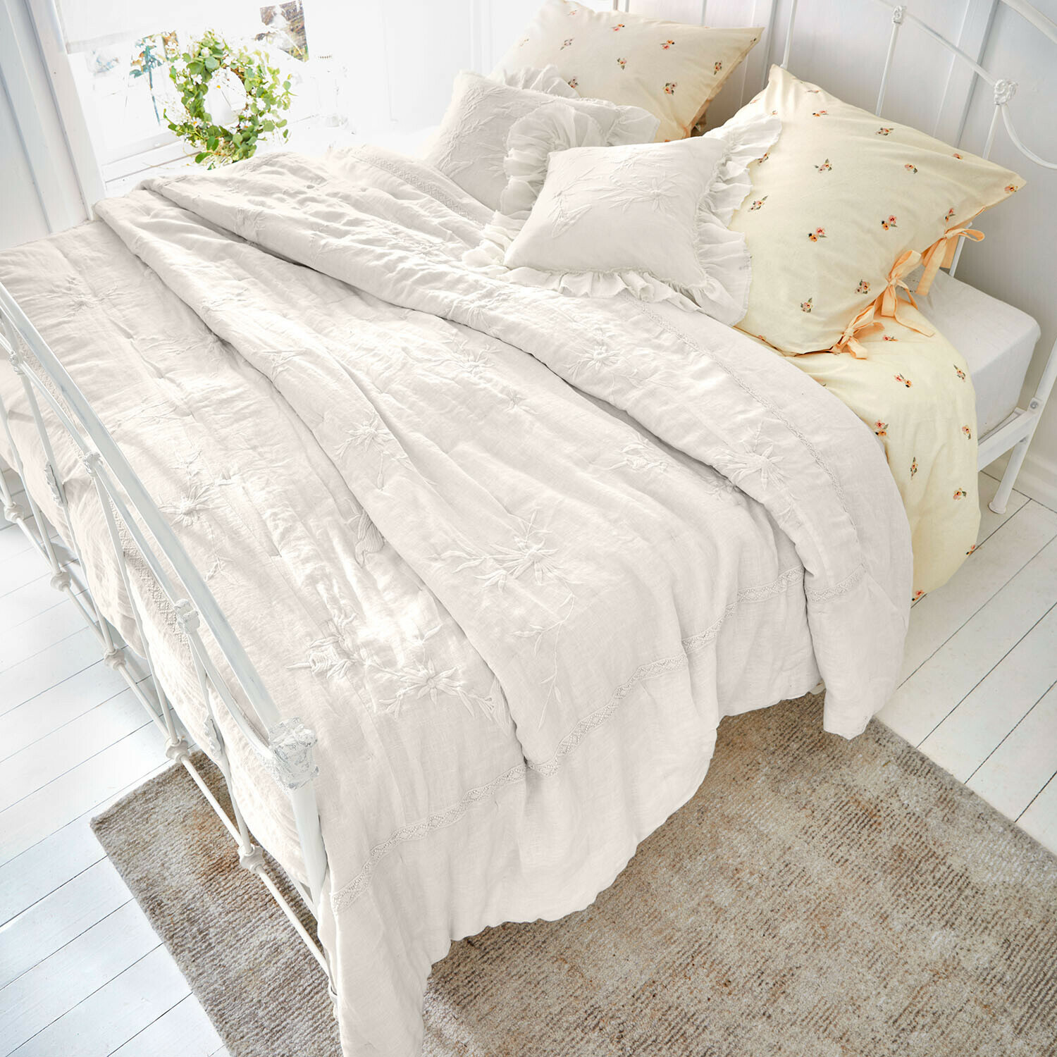 Colcha Norwyn Ropa de cama de lino color crema con bordados florales y cojines decorativos, ambiente acogedor en dormitorio