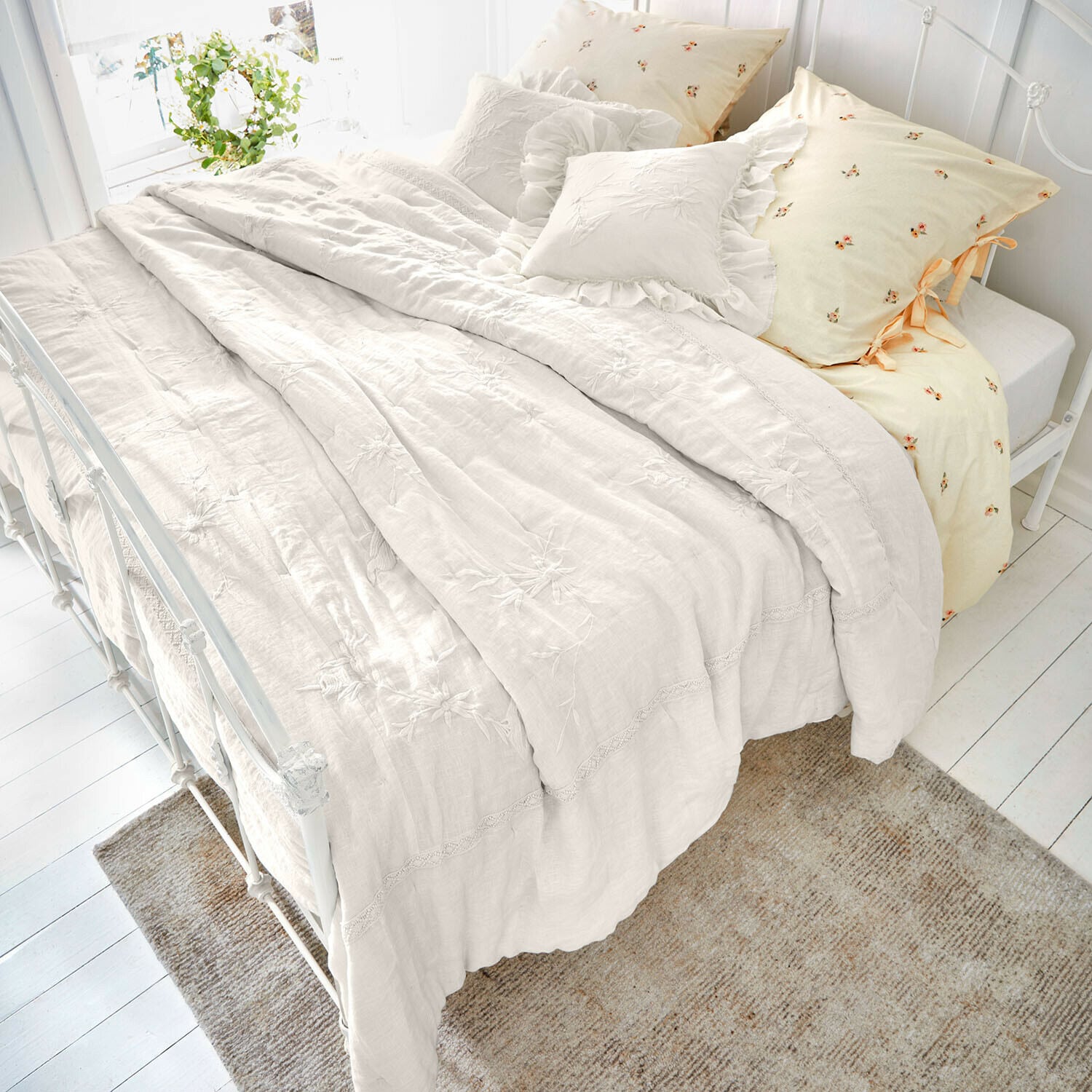 Colcha Norwyn Ropa de cama de lino color crema con bordados florales y cojines decorativos, ambiente acogedor en dormitorio
