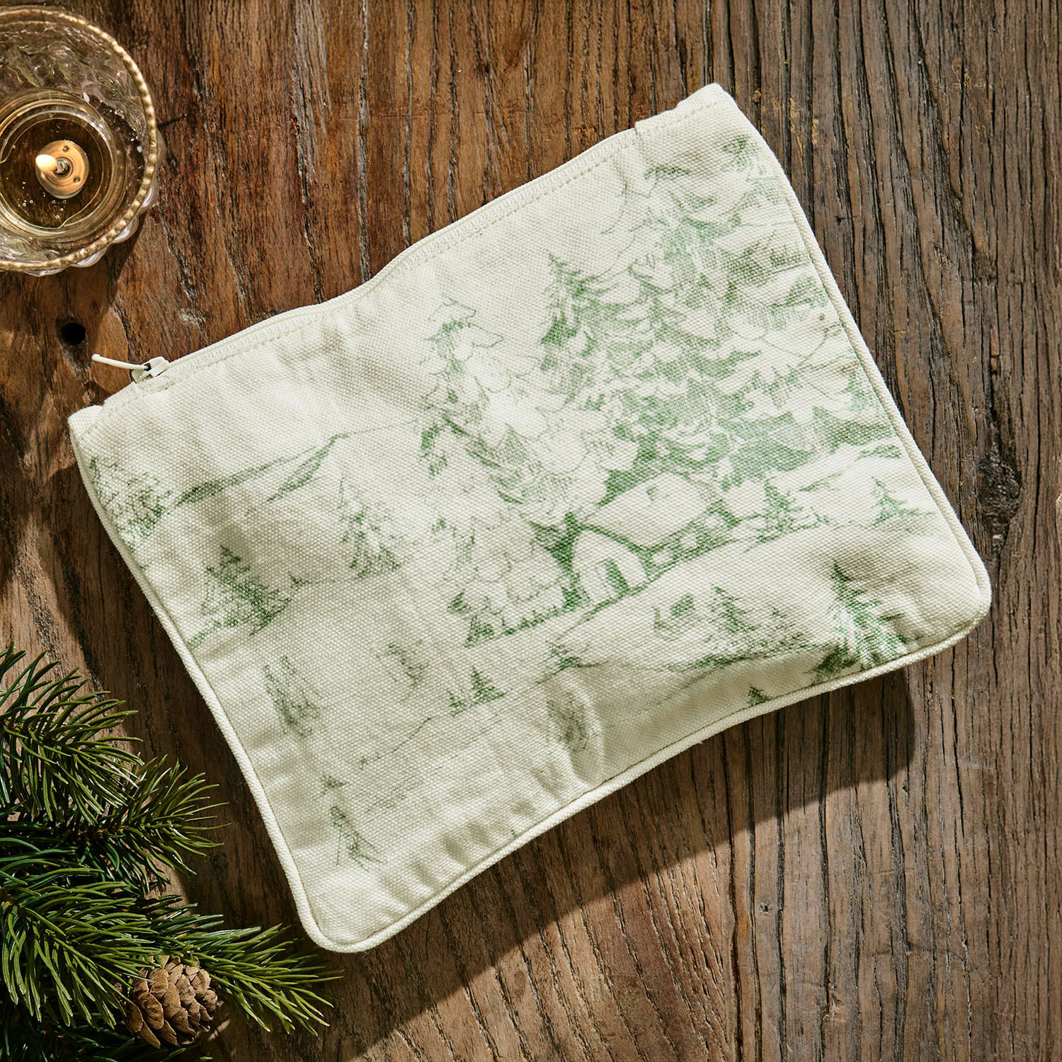 Bolsita Norathia Neceser beige de algodón con estampado verde de paisaje forestal sobre mesa de madera