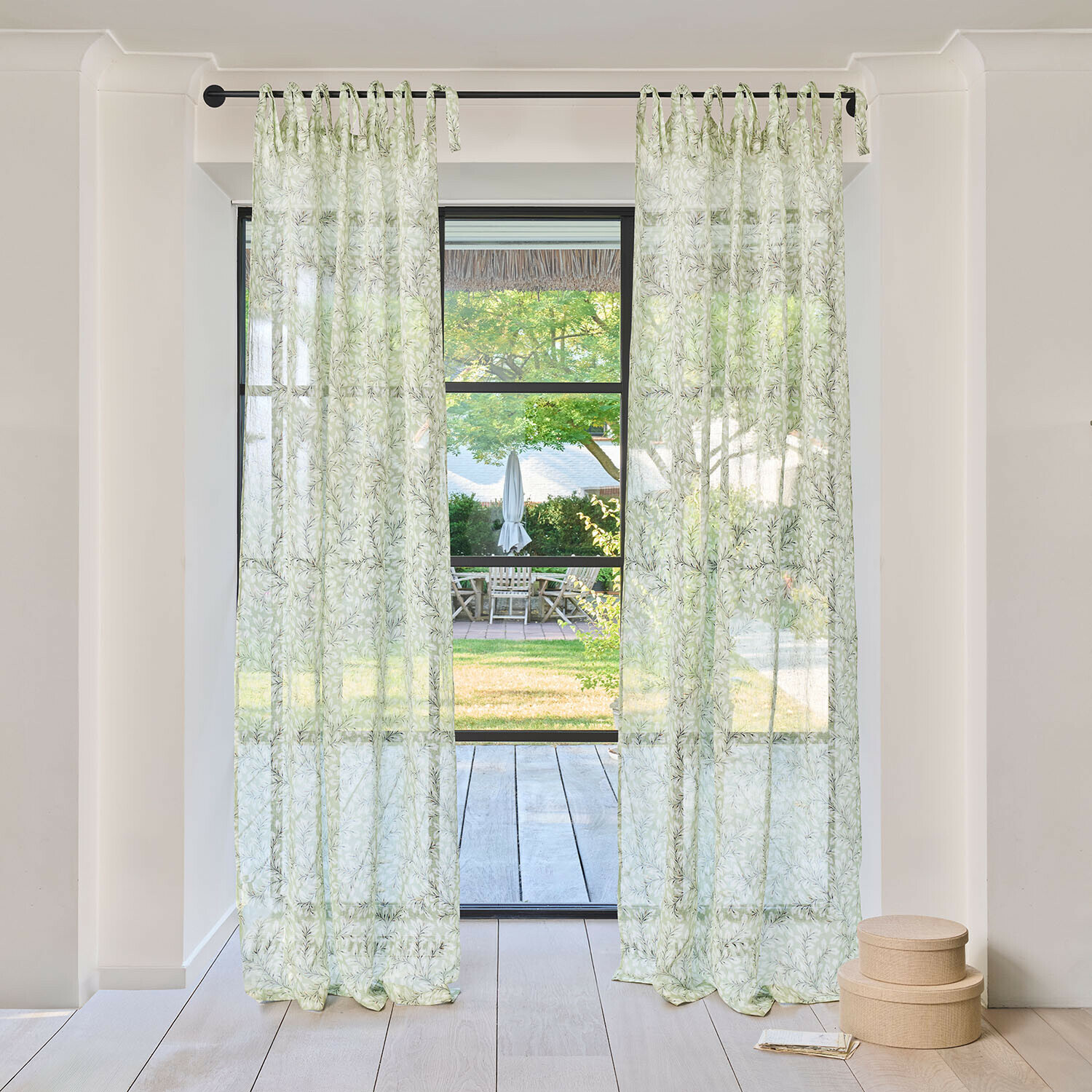 Cortina Norelline Cortinas transparentes con diseño de hojas verdes en barra negra en habitación luminosa con vista al jardín