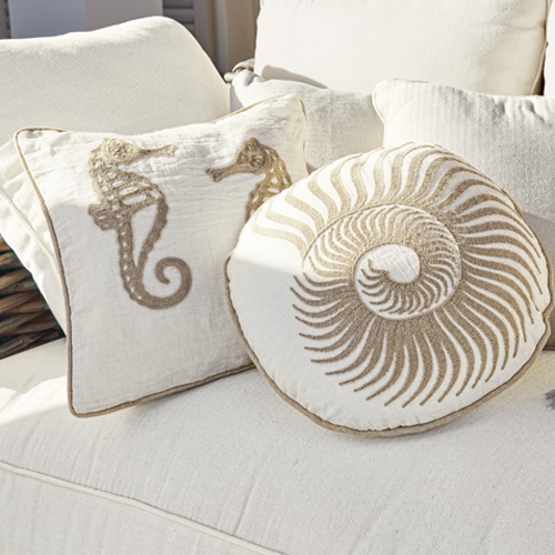 Cojines decorativos de algodón crema con motivos de caballito de mar y concha en sofá claro
