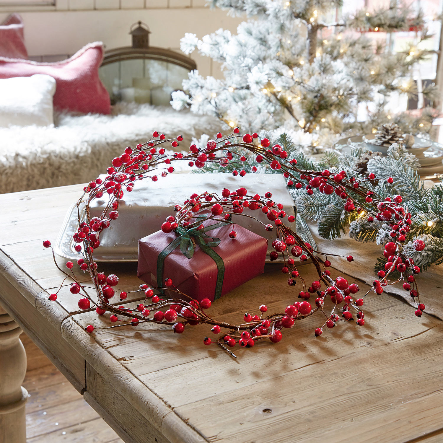 Guirnalda Rimont Corona decorativa de bayas rojas sobre mesa de madera con regalo y decoración navideña