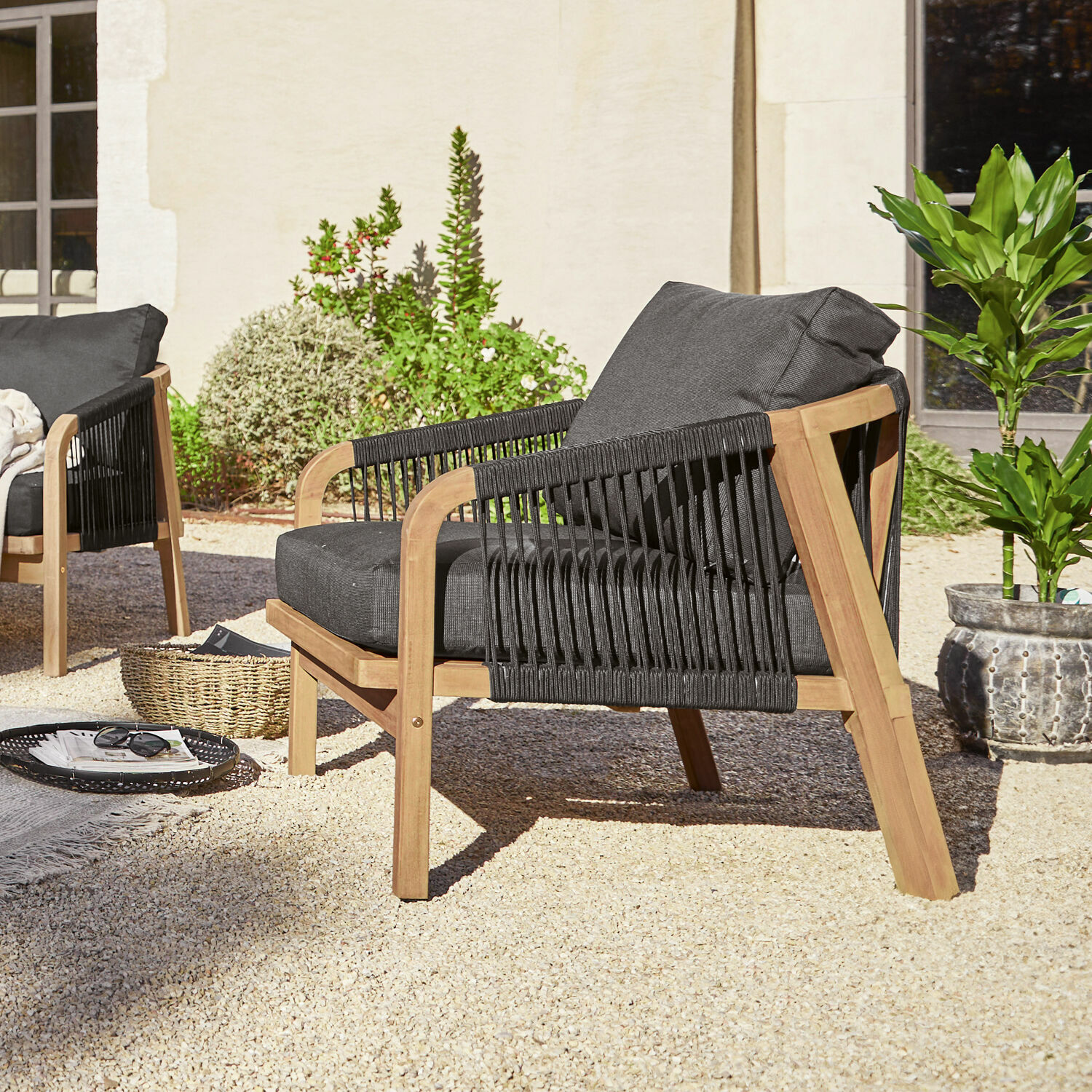 Sillón de jardín de madera con tela negra y cojines, ideal para relajarse al aire libre