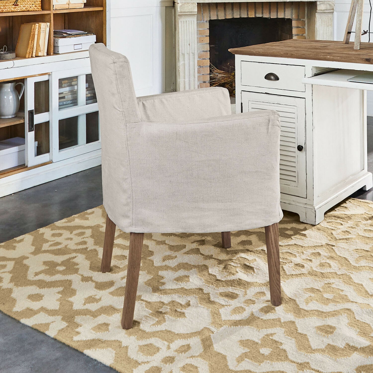 Silla Longhill Sillón beige de tela con patas de madera sobre alfombra con patrón en interior acogedor con chimenea
