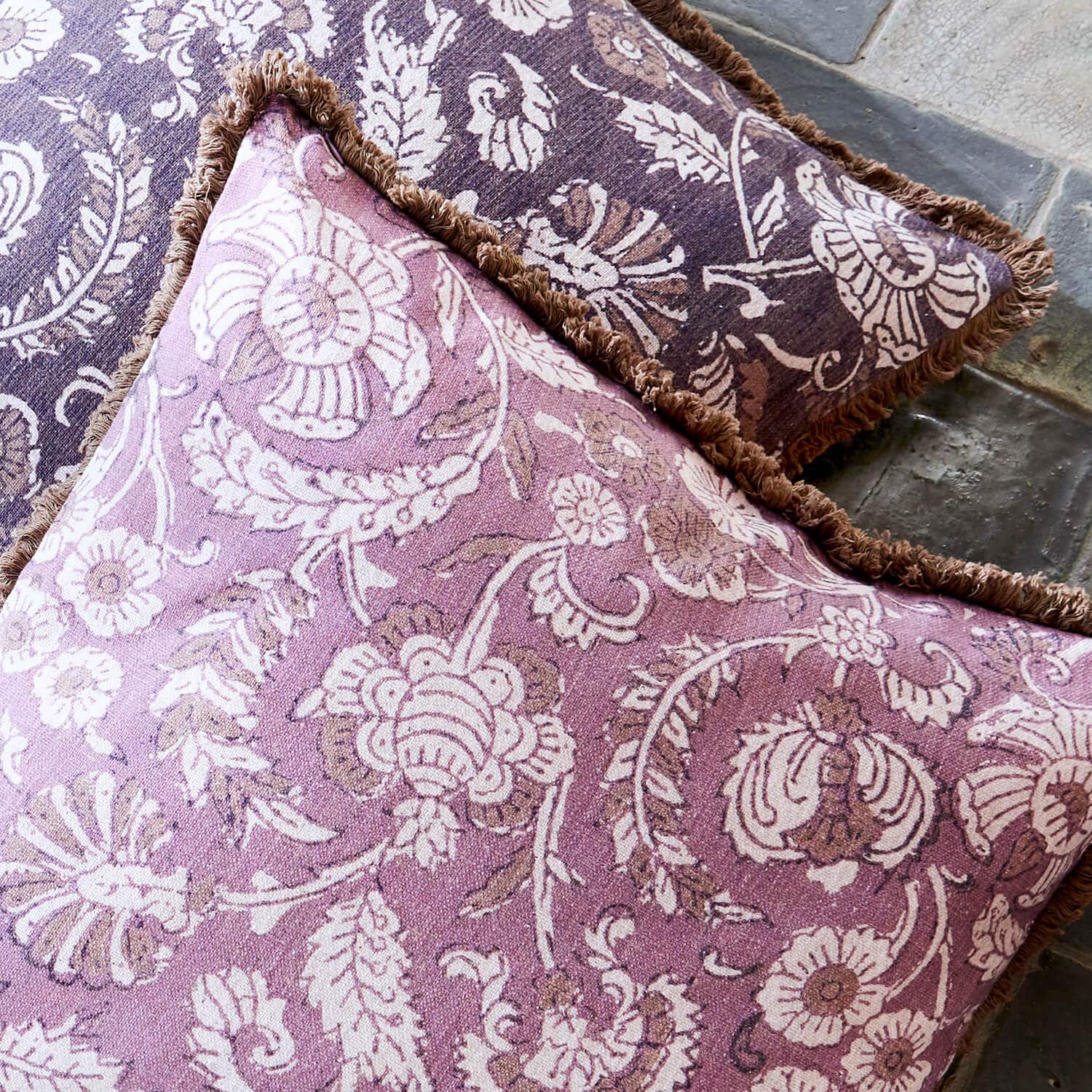 Cojín decorativo reversible de algodón con estampado floral en tonos morado y marrón con flecos