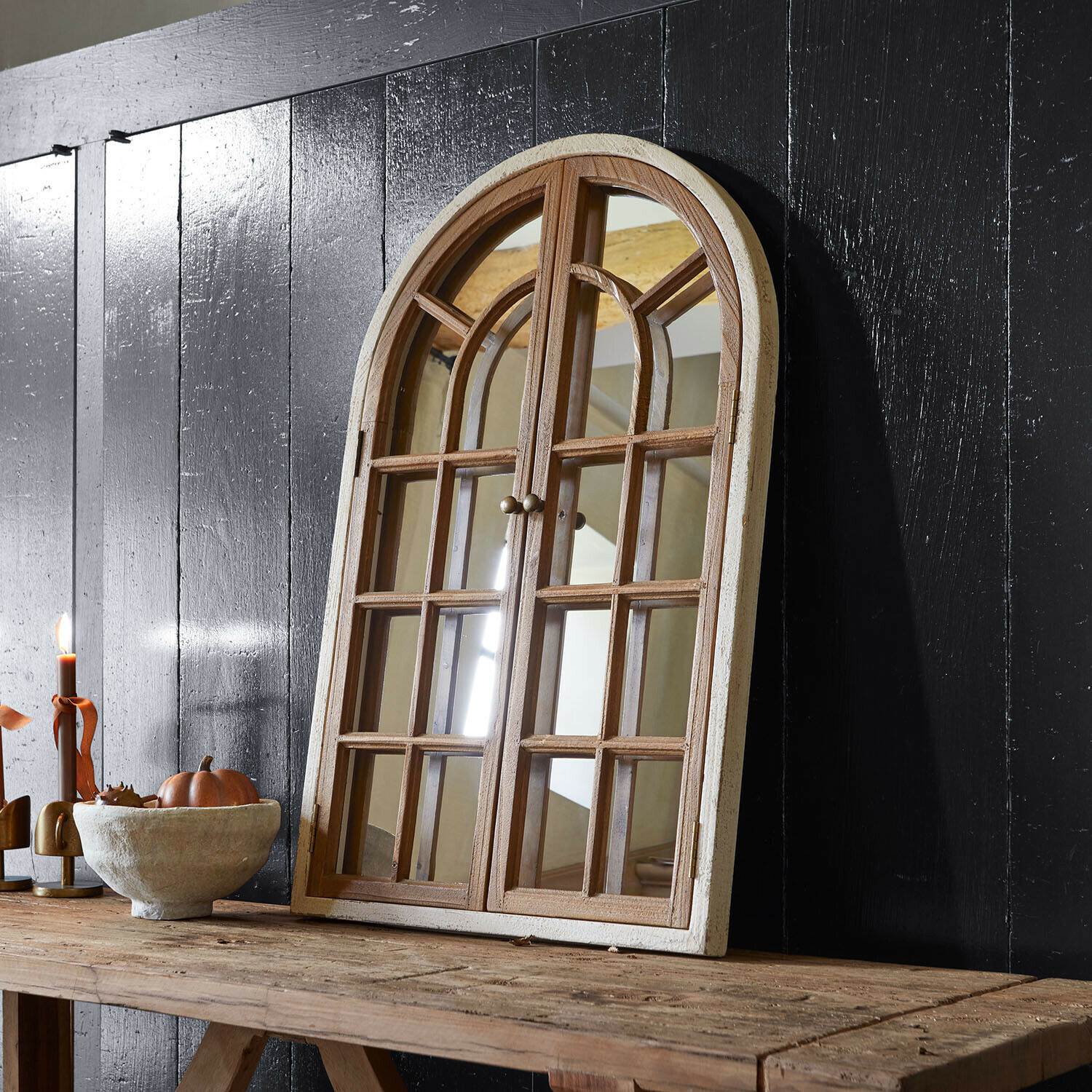 Ventana decorativa con espejo Montévine Espejo de madera con forma de ventana y marco blanco sobre mesa rústica frente a pared negra