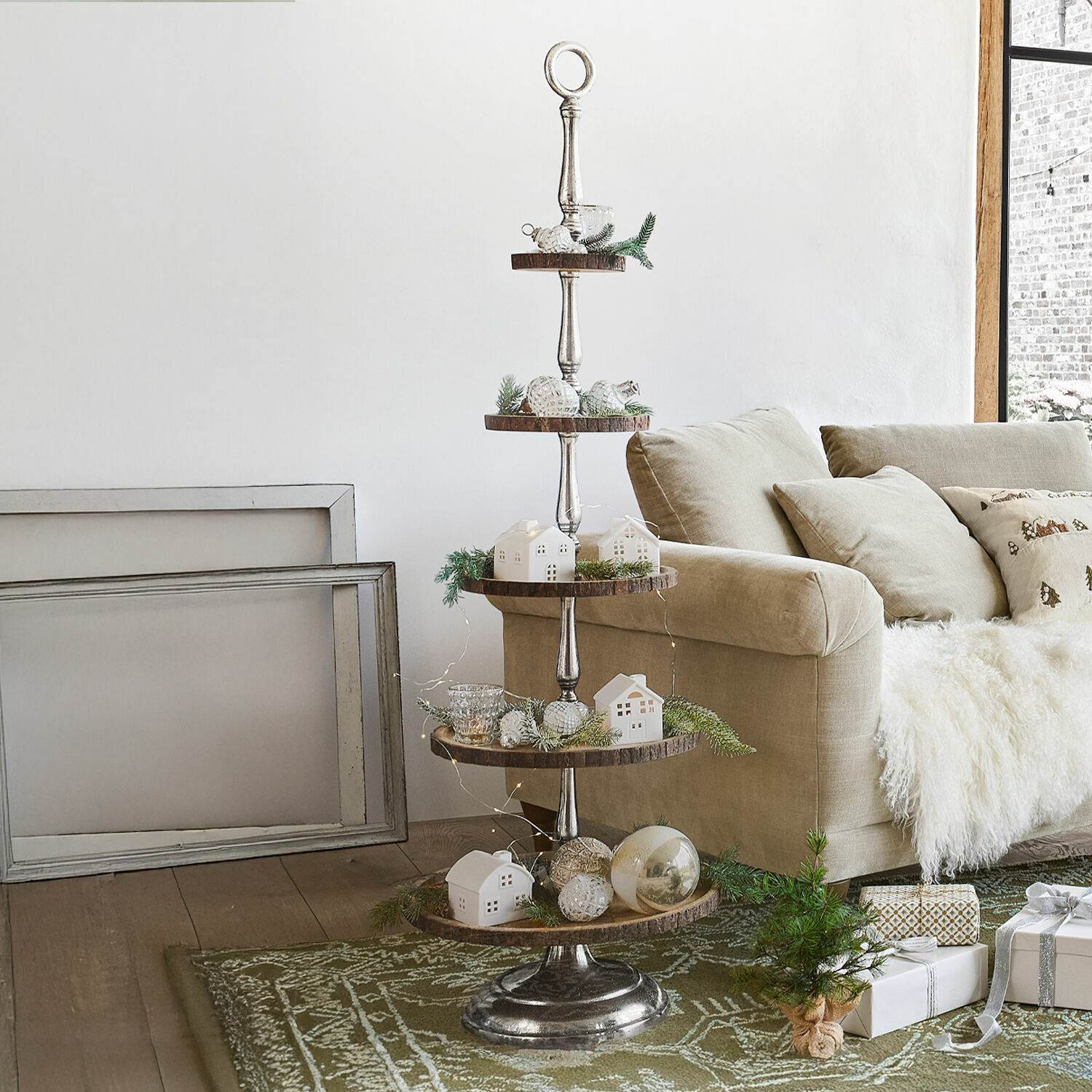 Soporte de varios niveles de metal y madera con aperitivos junto a sofá beige y decoración de salón