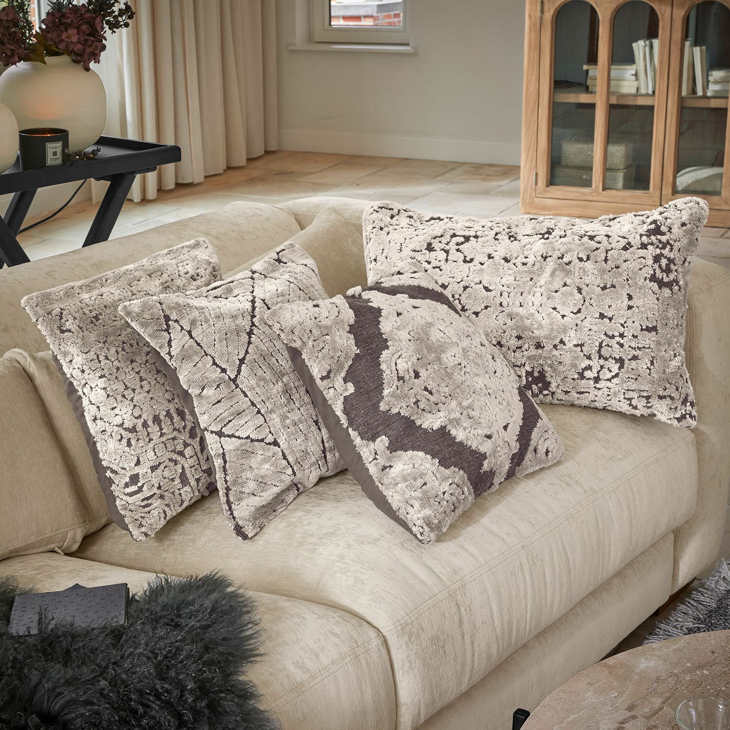 Set de 4 fundas de cojín Plaisancière Conjunto de cuatro cojines decorativos de tela suave en tonos beige y marrón sobre un sofá claro