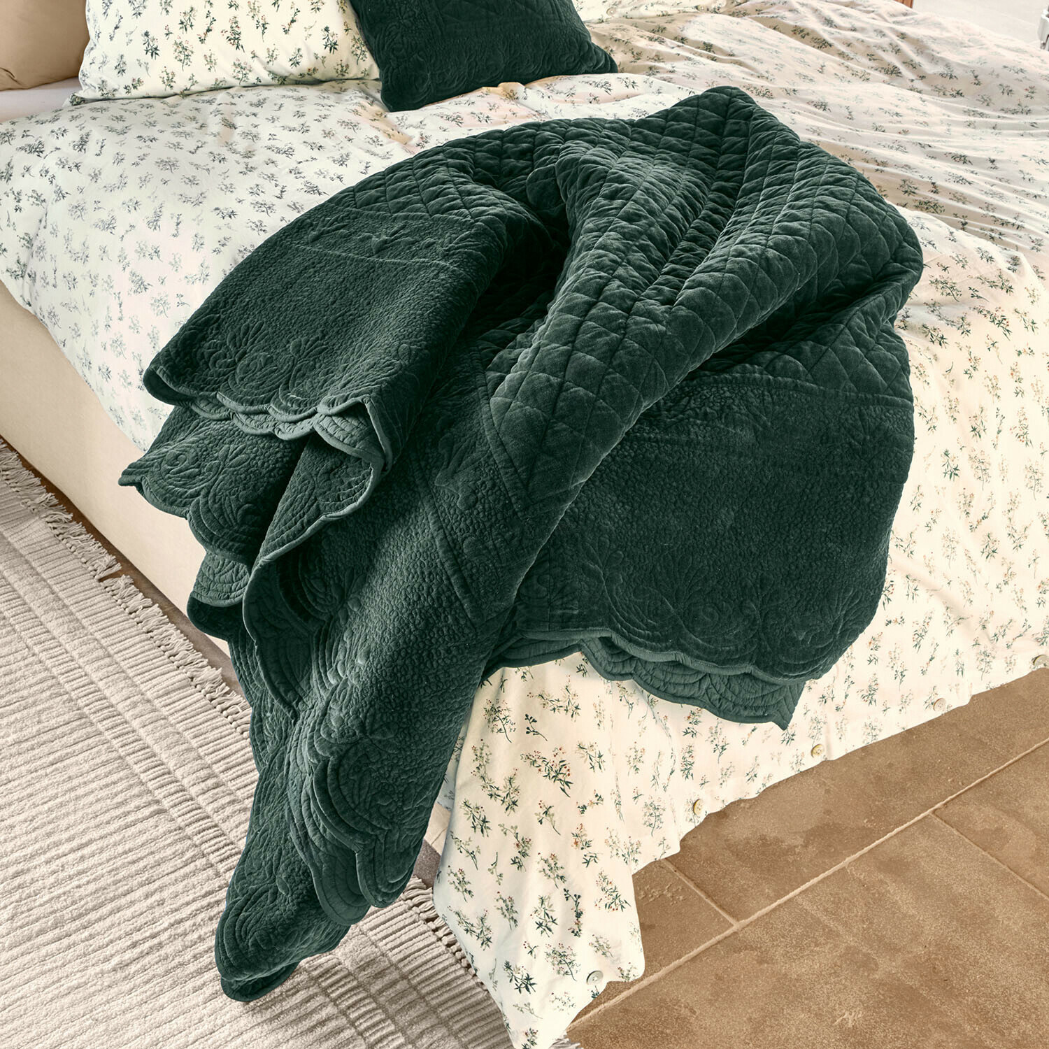 Colcha Lunévois Manta acolchada verde oscuro de material suave sobre cama con ropa de cama clara y estampado floral