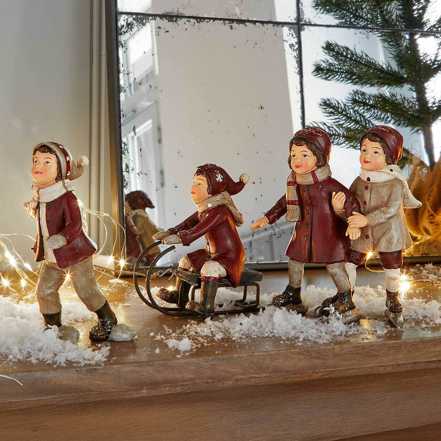 Figuras de niños con ropa de invierno con trineo y patines sobre superficie de madera con decoración de nieve