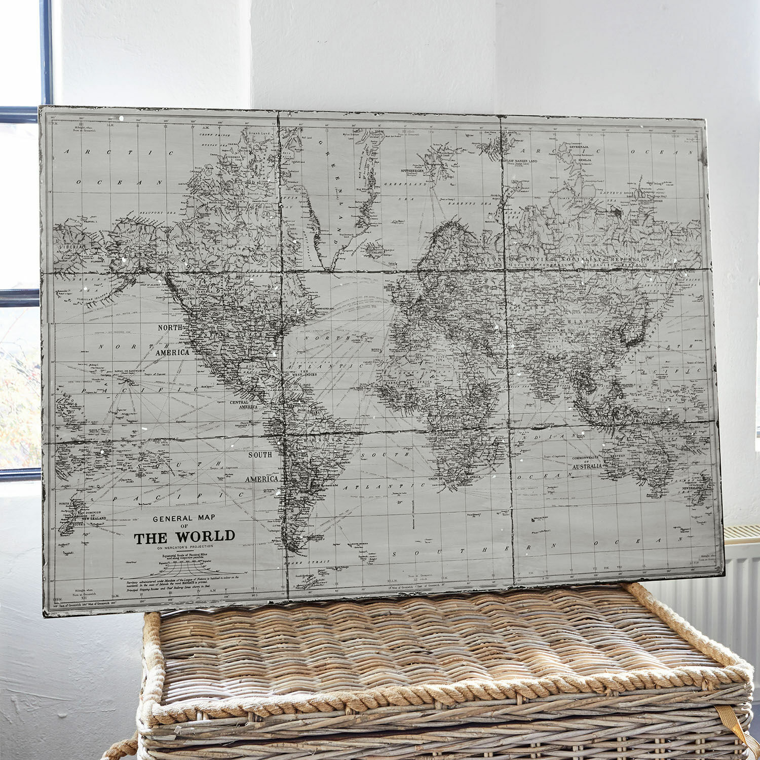 Cuadro Macolin Mapa mundial vintage en tonos grises sobre cesta de mimbre para decoración interior