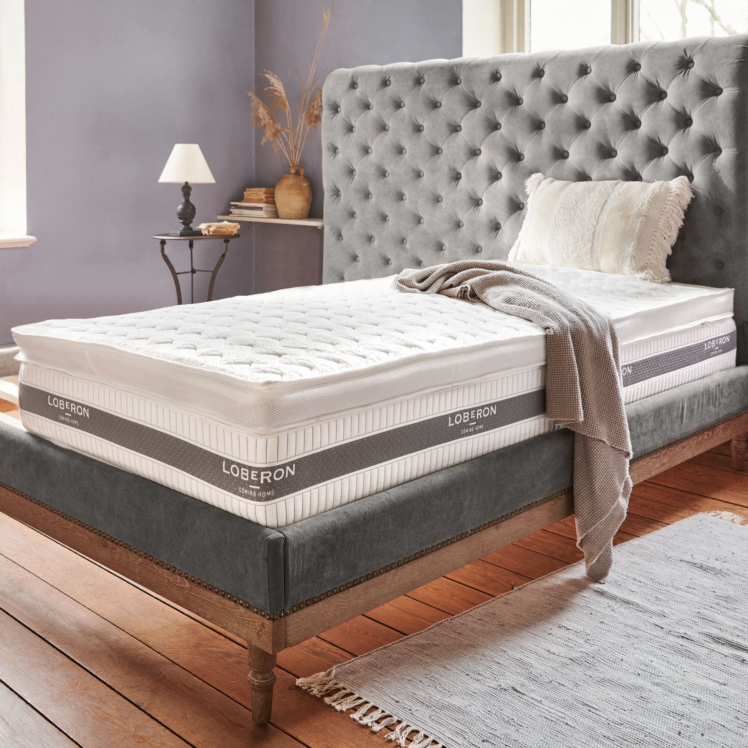 Topper Danisar Cama tapizada gris con colchón blanco Loberon y manta beige en dormitorio acogedor