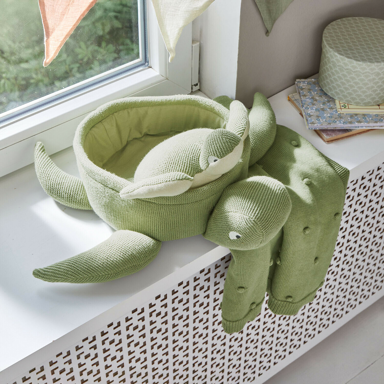 Cojín verde tejido en forma de tortuga sobre el alféizar, decoración suave para habitación infantil