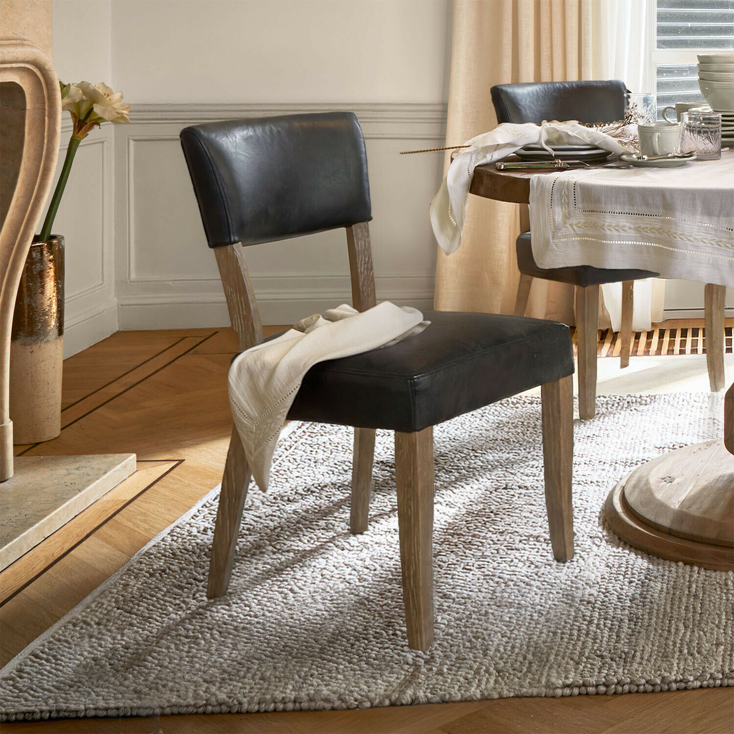 Silla Norevaux Silla de comedor con tapizado de cuero negro y patas de madera sobre alfombra clara en sala elegante