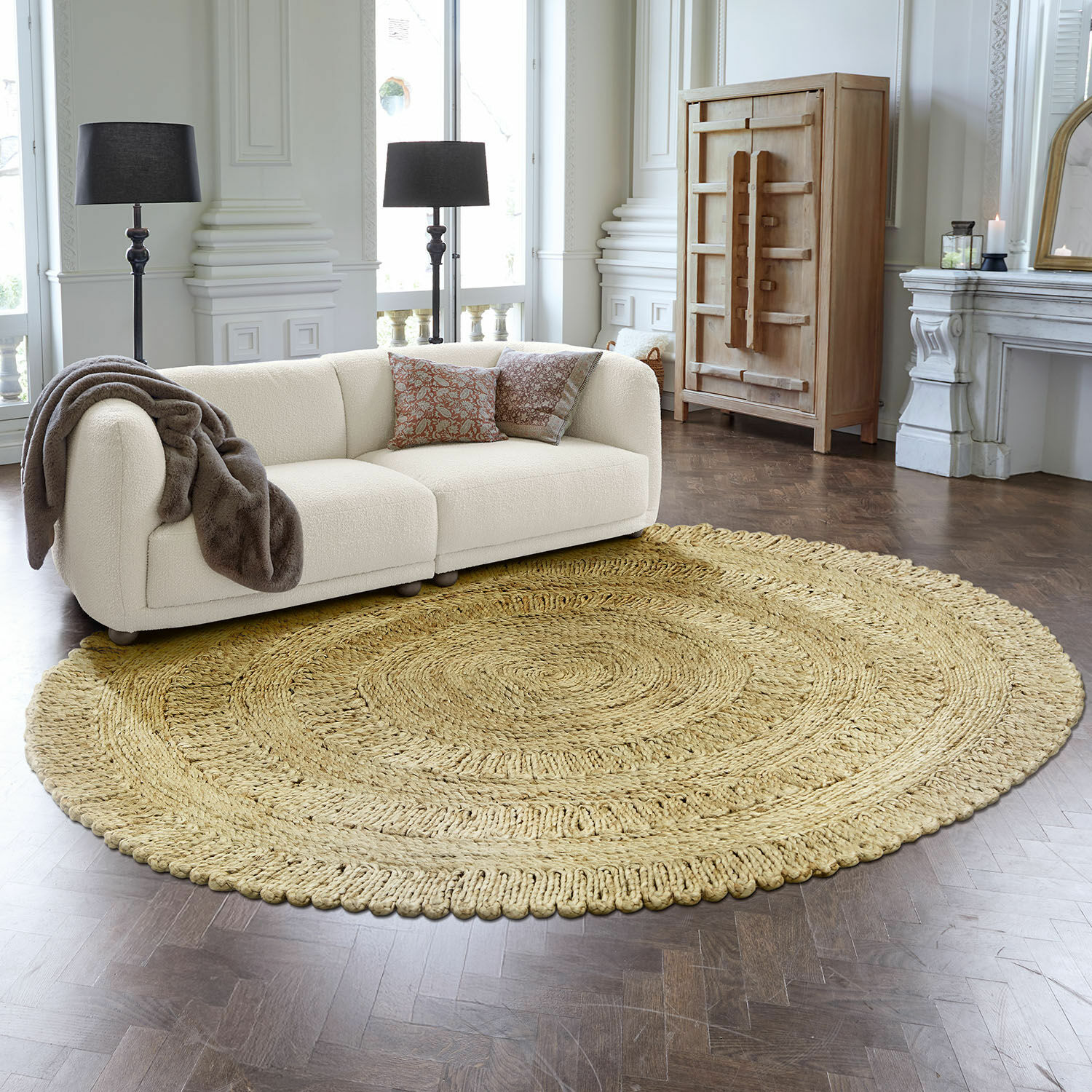 Alfombra Arendel Alfombra redonda de material natural beige en sala moderna con sofá blanco y lámparas negras