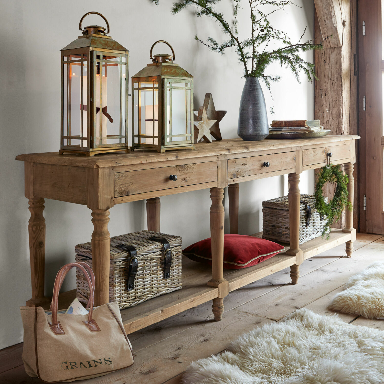 Consola Misérieux Consola de madera con tres cajones, faroles decorativos y cestas de mimbre en ambiente acogedor