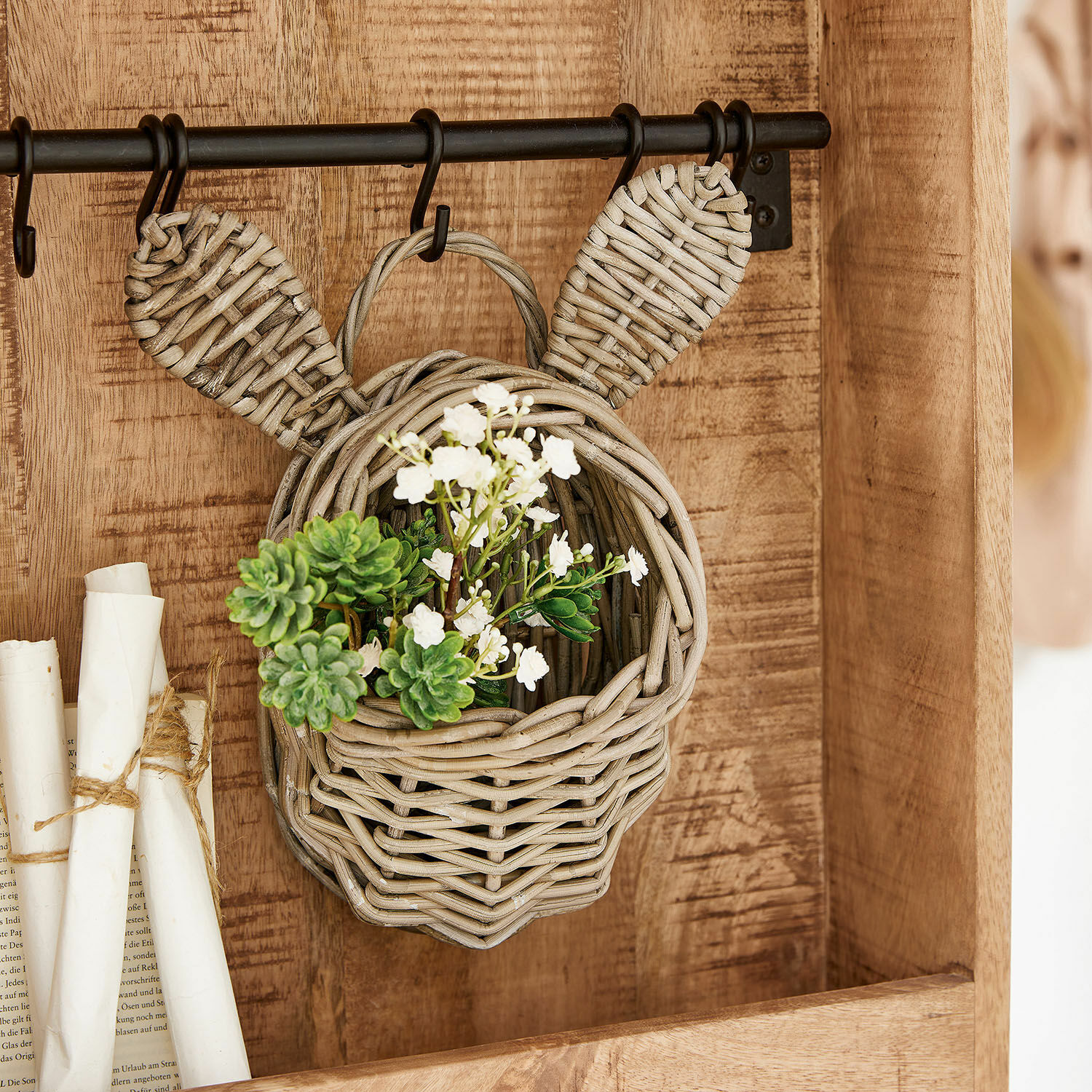 Cesta Frances Cesta colgante de ratán con forma de cabeza y orejas, decorada con flores blancas y verdes