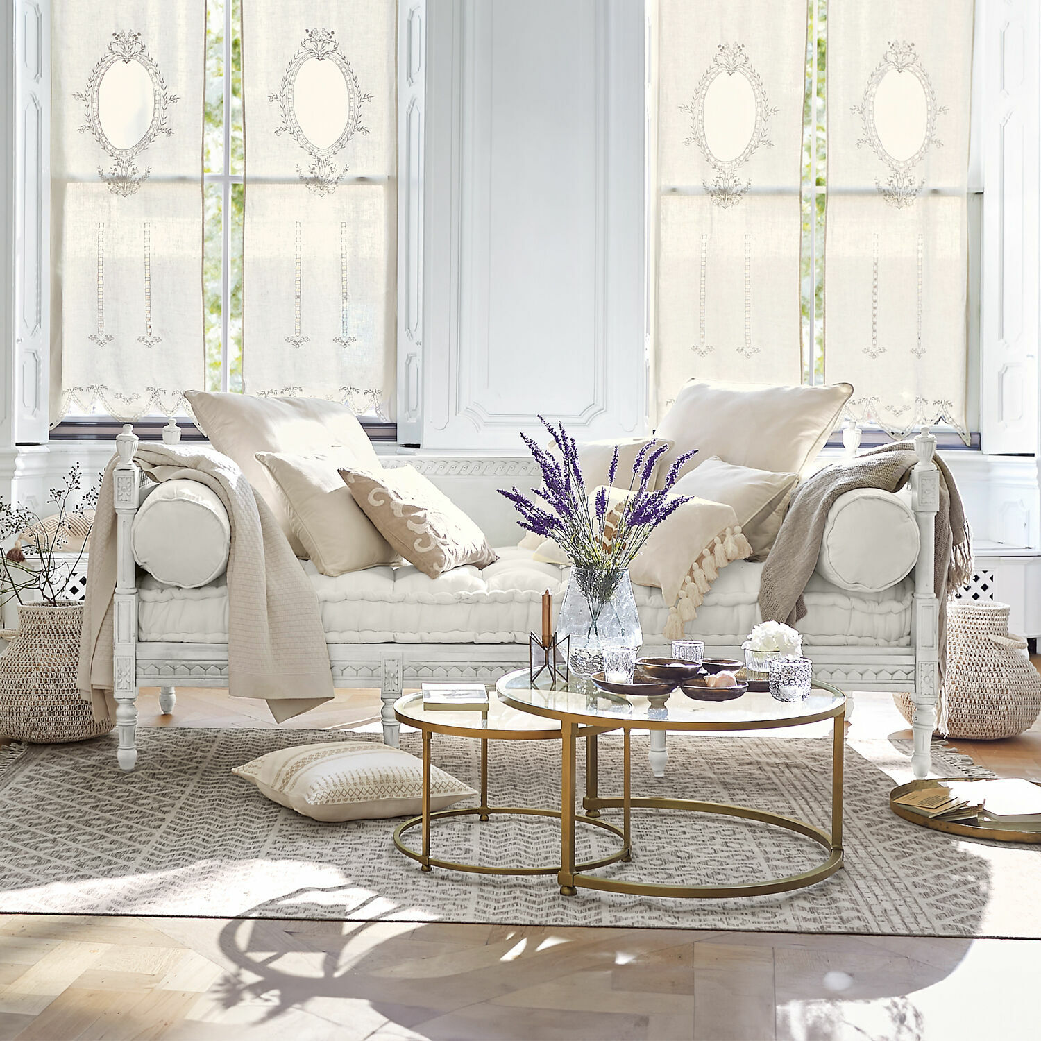 Sofá Douville Sofá de madera blanca con cojines crema y mesa de centro dorada en sala luminosa