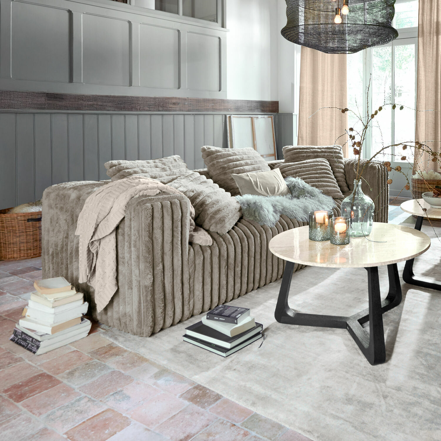 Sofá Roucemont Sofá beige de felpa suave con cojines y manta en salón moderno con mesa de mármol