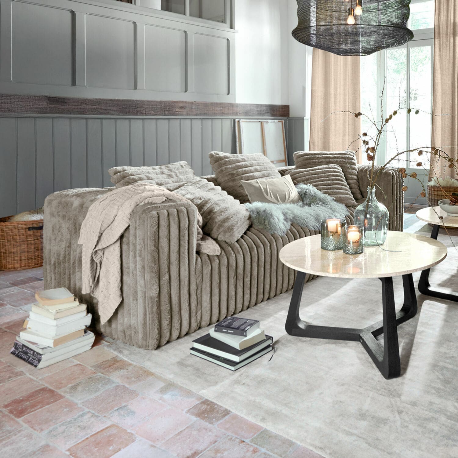 Sofá Roucemont Sofá beige de felpa suave con cojines y manta en salón moderno con mesa de mármol