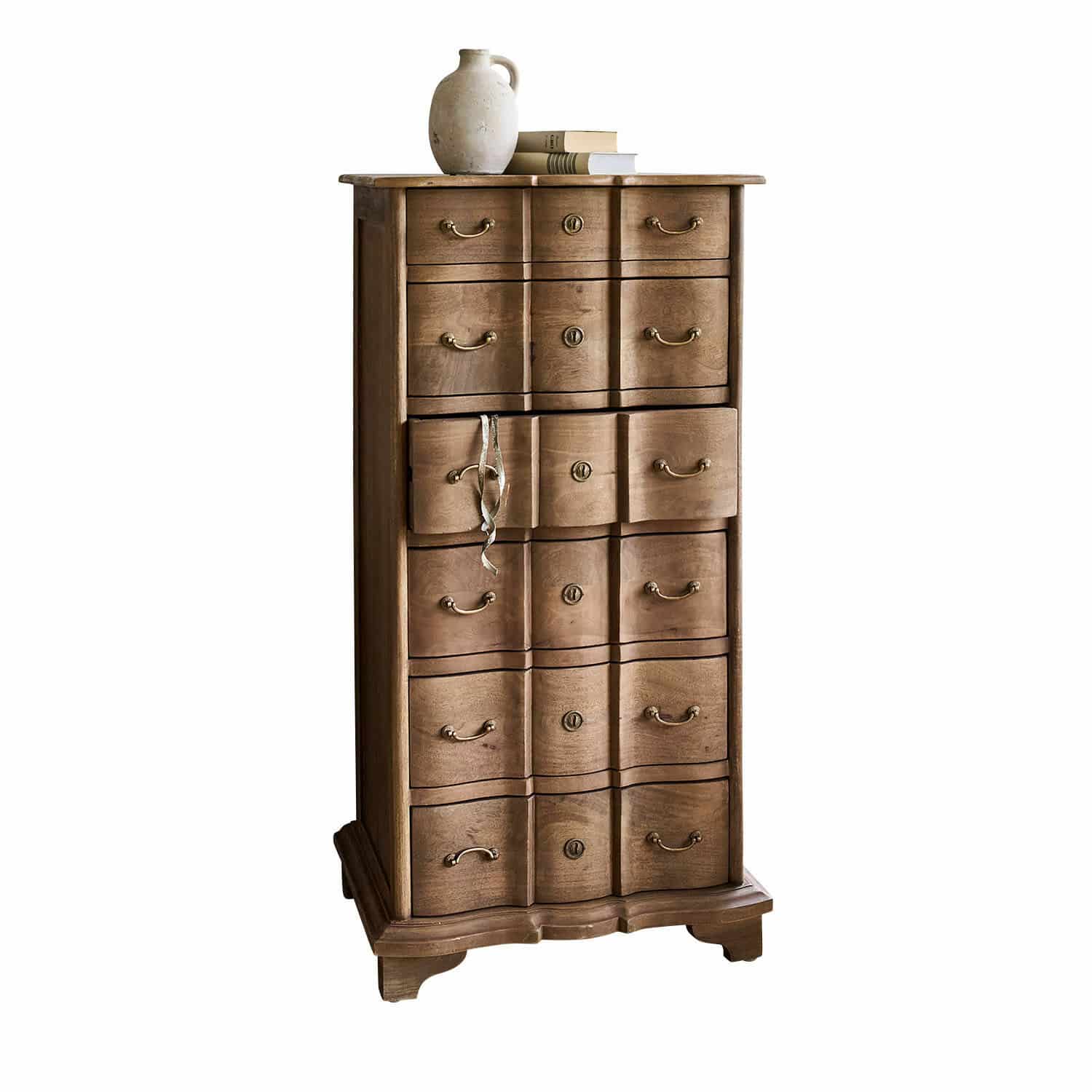 Cómoda Aiguillon Cómoda alta de madera natural con varios cajones y jarra de cerámica sobre libros